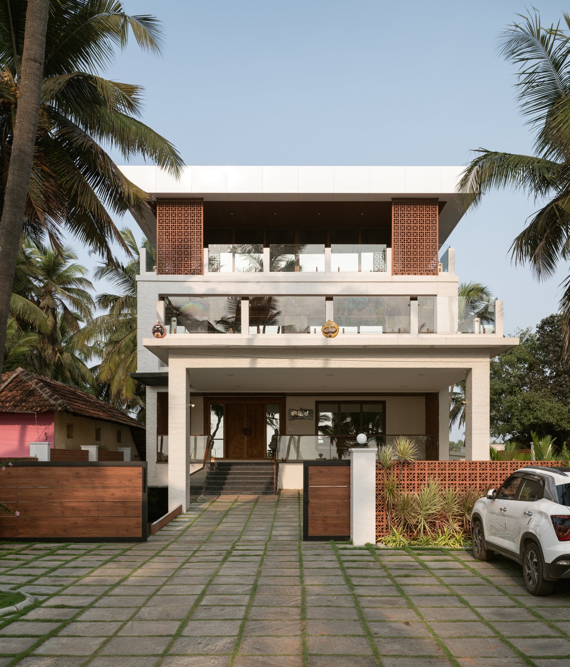 The facade, where terracotta jaali screens and a carved wooden door announce the home's material vocabulary
