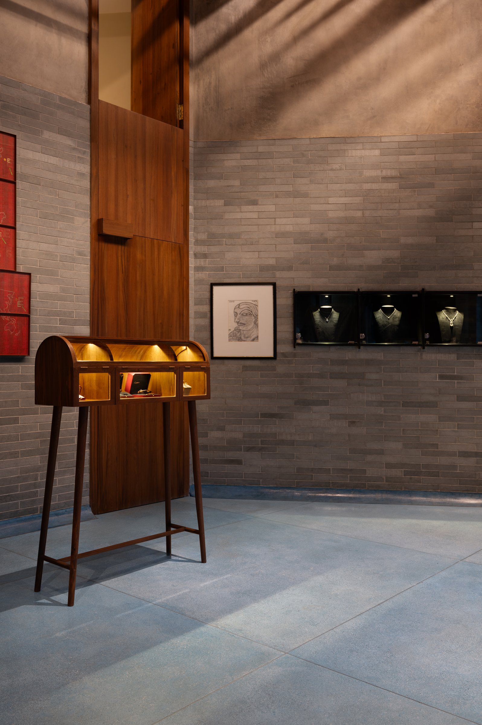 Shallow black display niches set into the brick wall, each jewellery bust pooled in its own light