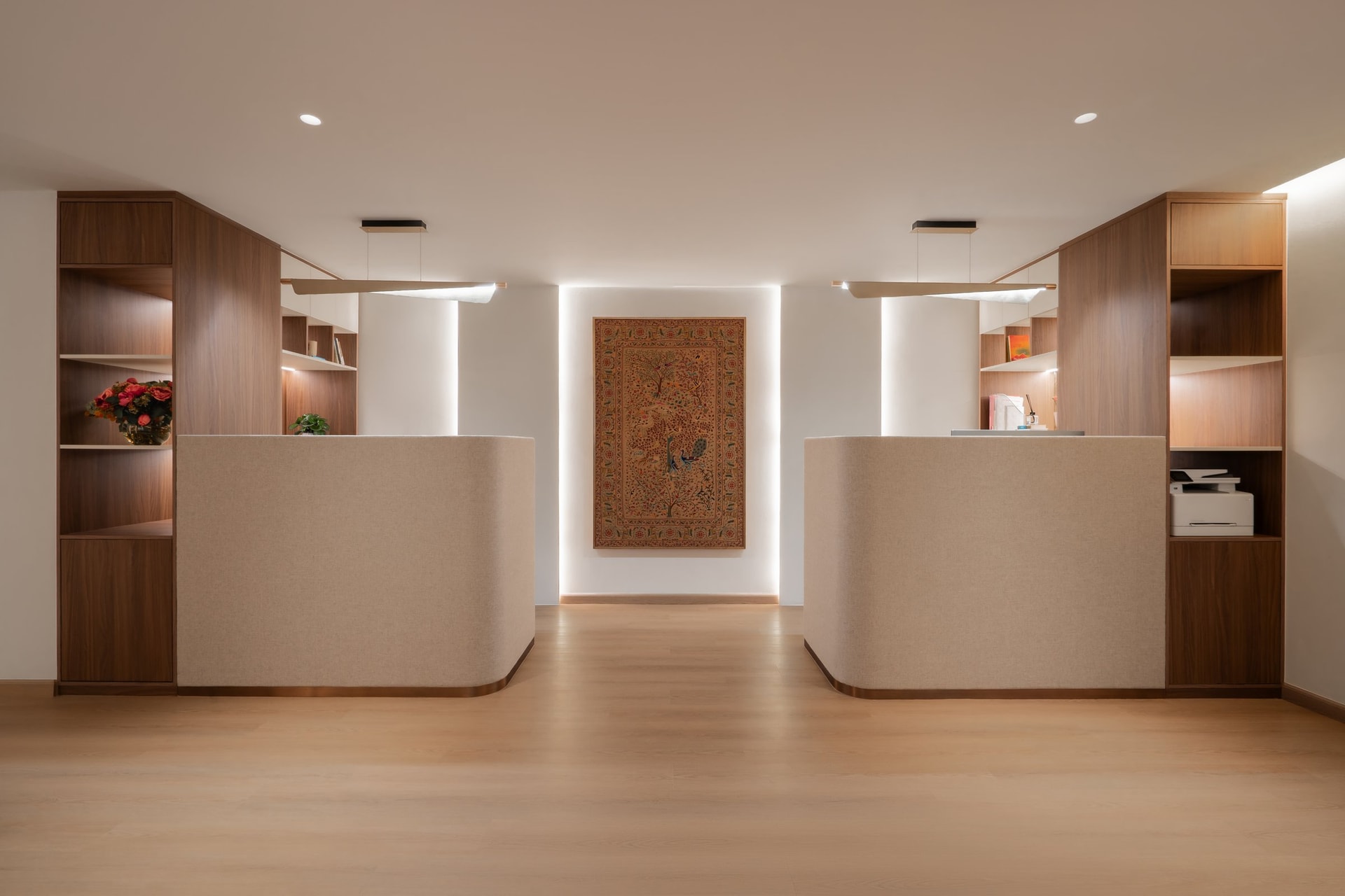 The reception, where two fabric-wrapped desks flank a backlit tree-of-life textile at the arrival threshold