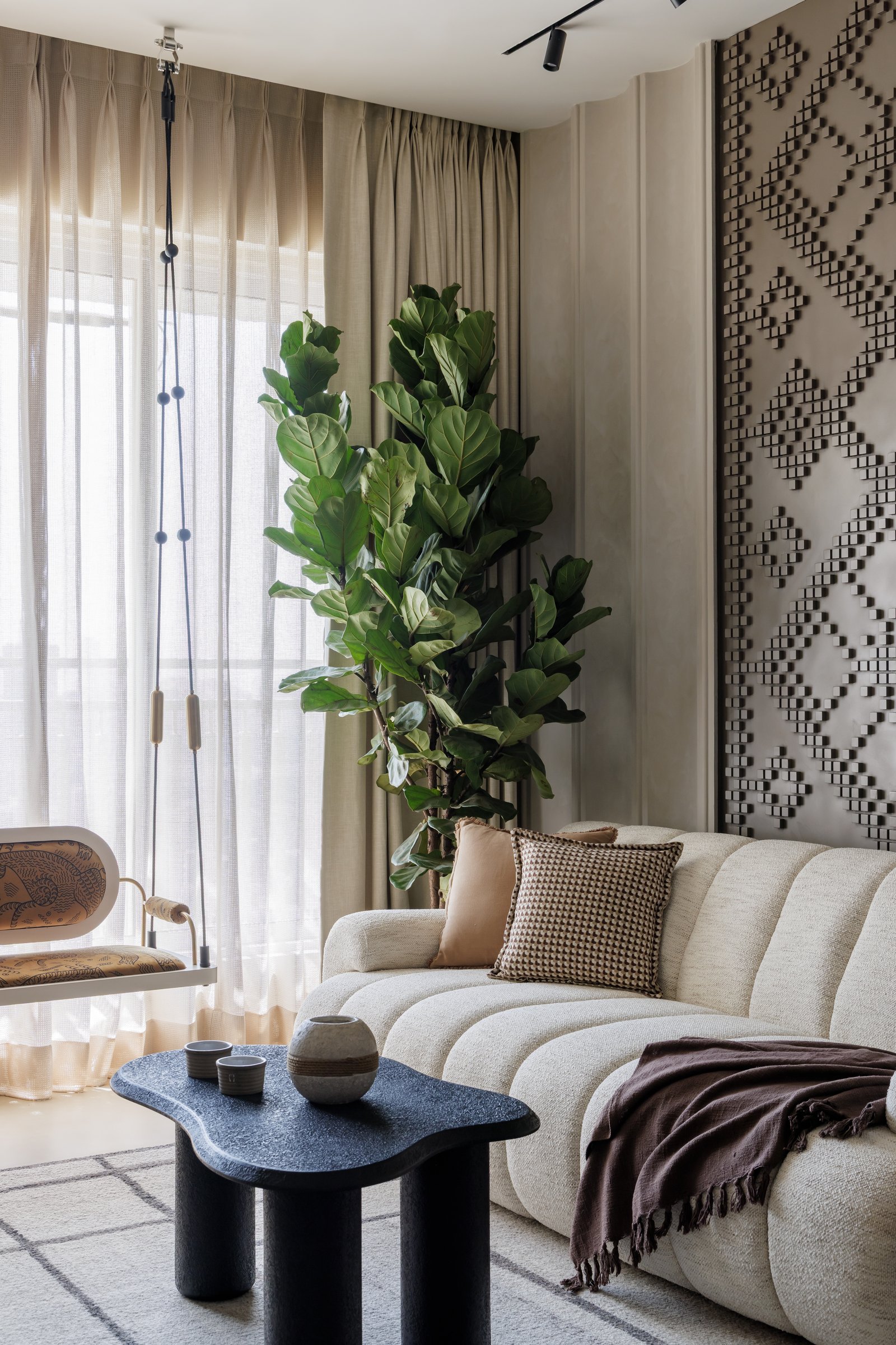 The living room, where a channelled bouclé sofa meets a full-height relief panel in soft taupe