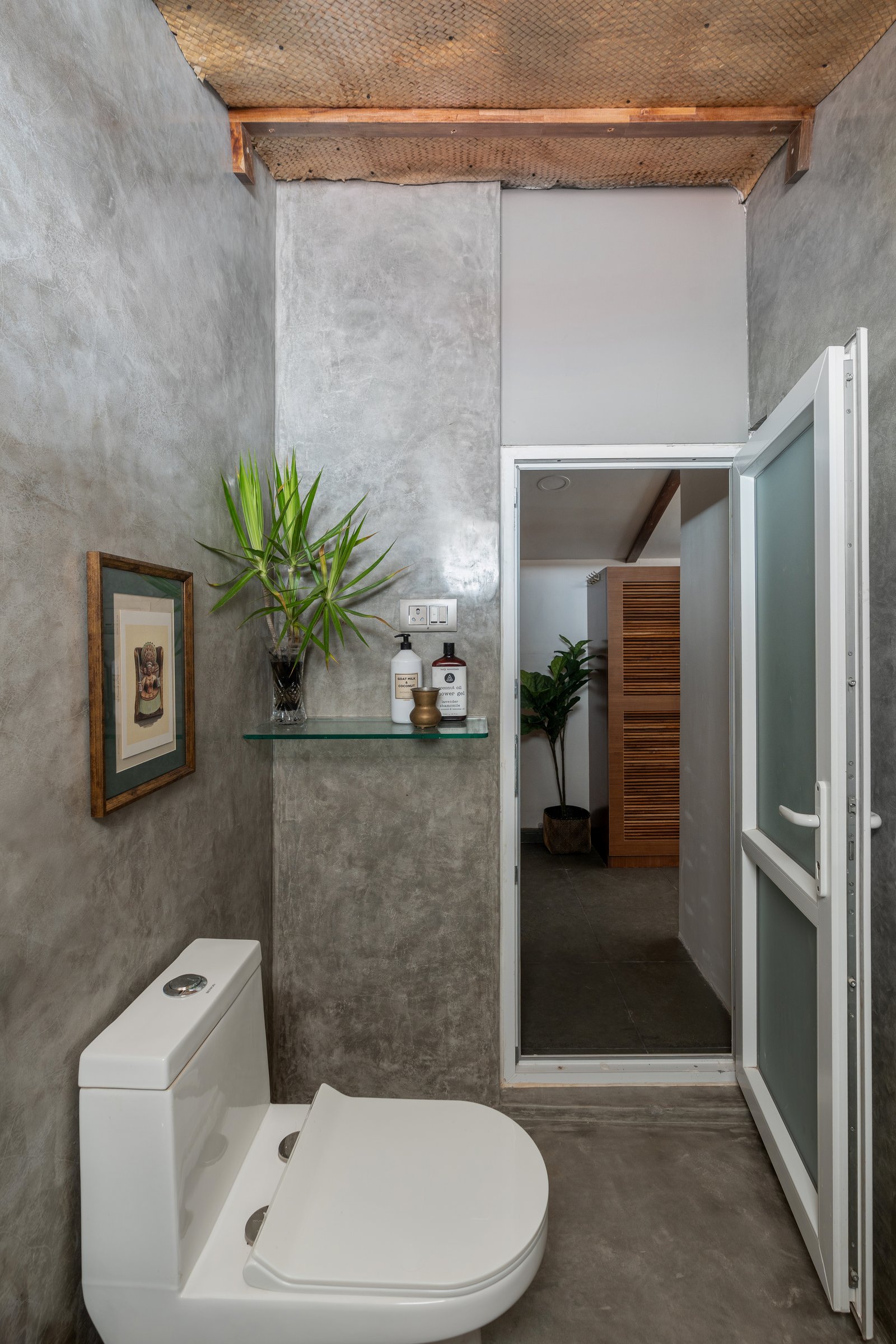 The toilet zone, where a woven bamboo ceiling lightens the enclosure of grey oxide walls