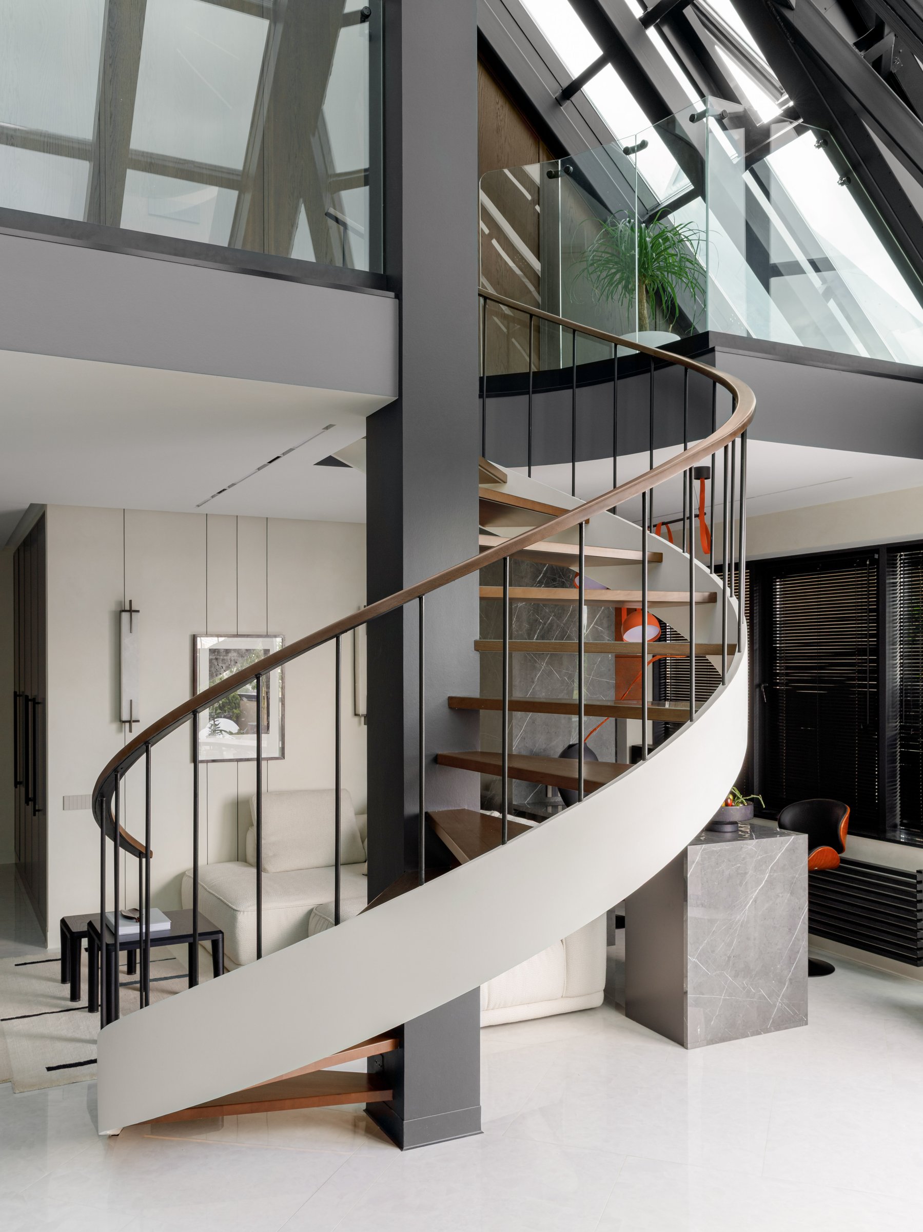 The staircase in full view, winding from polished floor to pitched glass roof