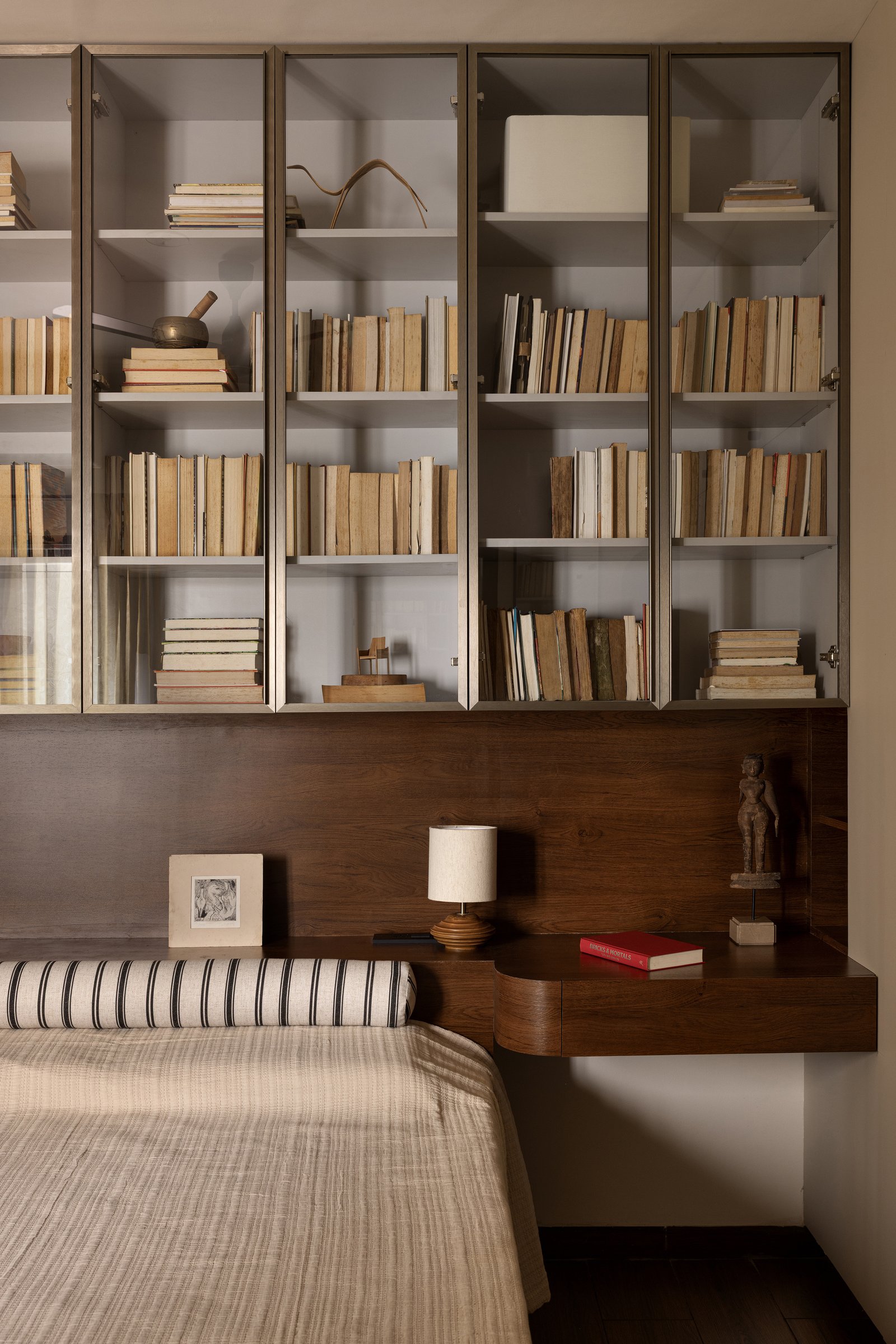 A closer view of the son's headboard wall, where the suspended library preserves a sense of lightness above the solid wood ledge