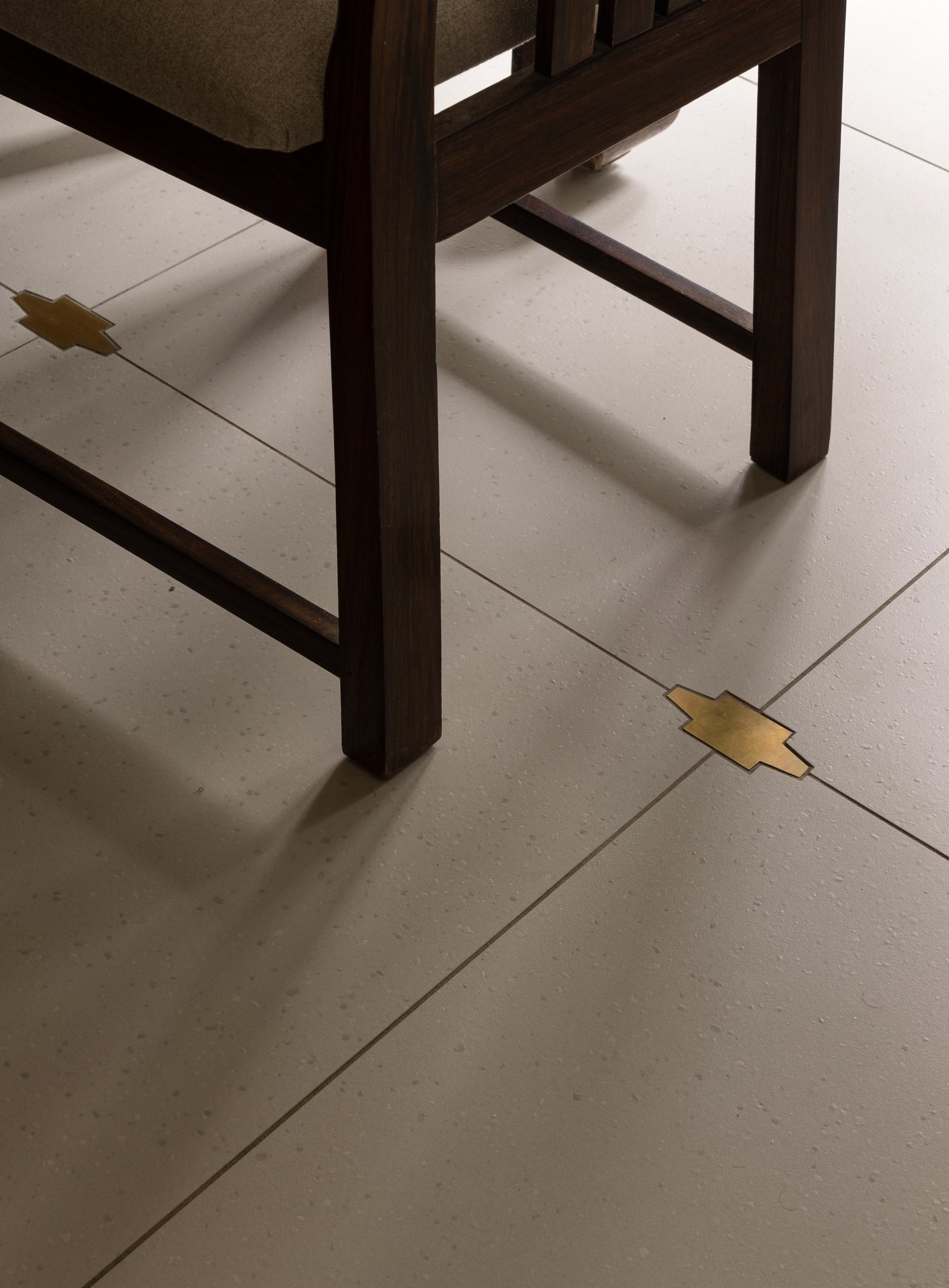 The floor, where custom brass inlays stand in for the tile traditions the project's timeline could not accommodate