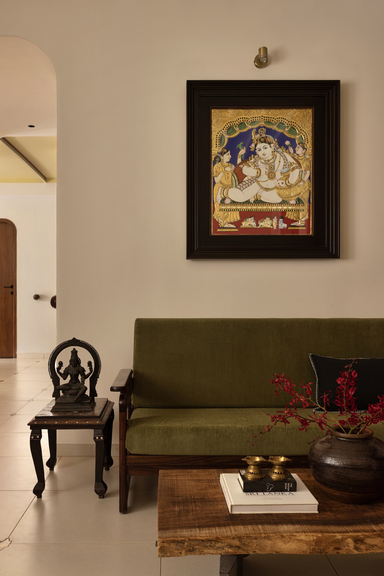 The living room, where a Tanjore painting and a heirloom rosewood settee in olive velvet establish the home's material register
