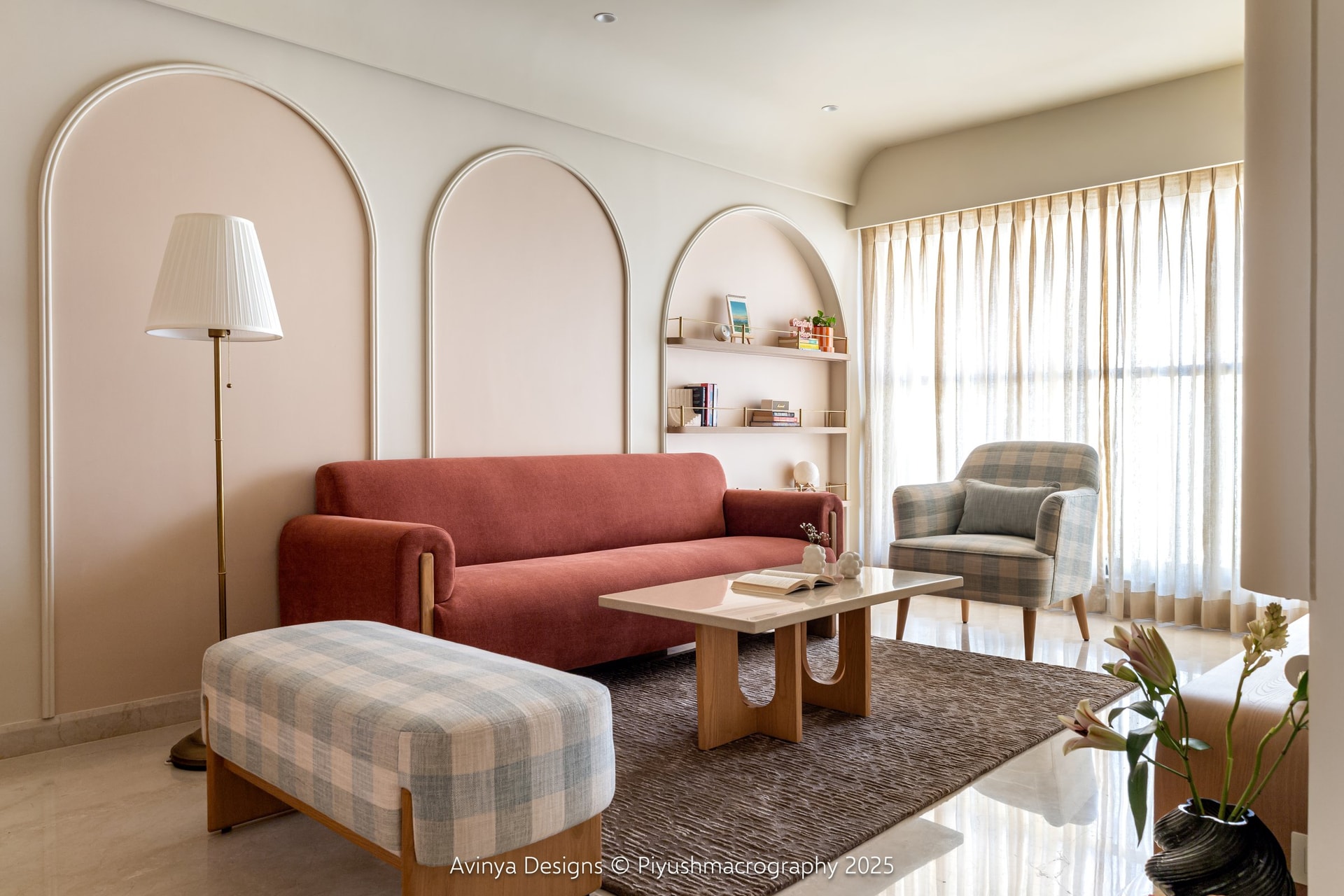 The living room, where three blush arched recesses and a rust upholstered sofa establish the home's warmest register