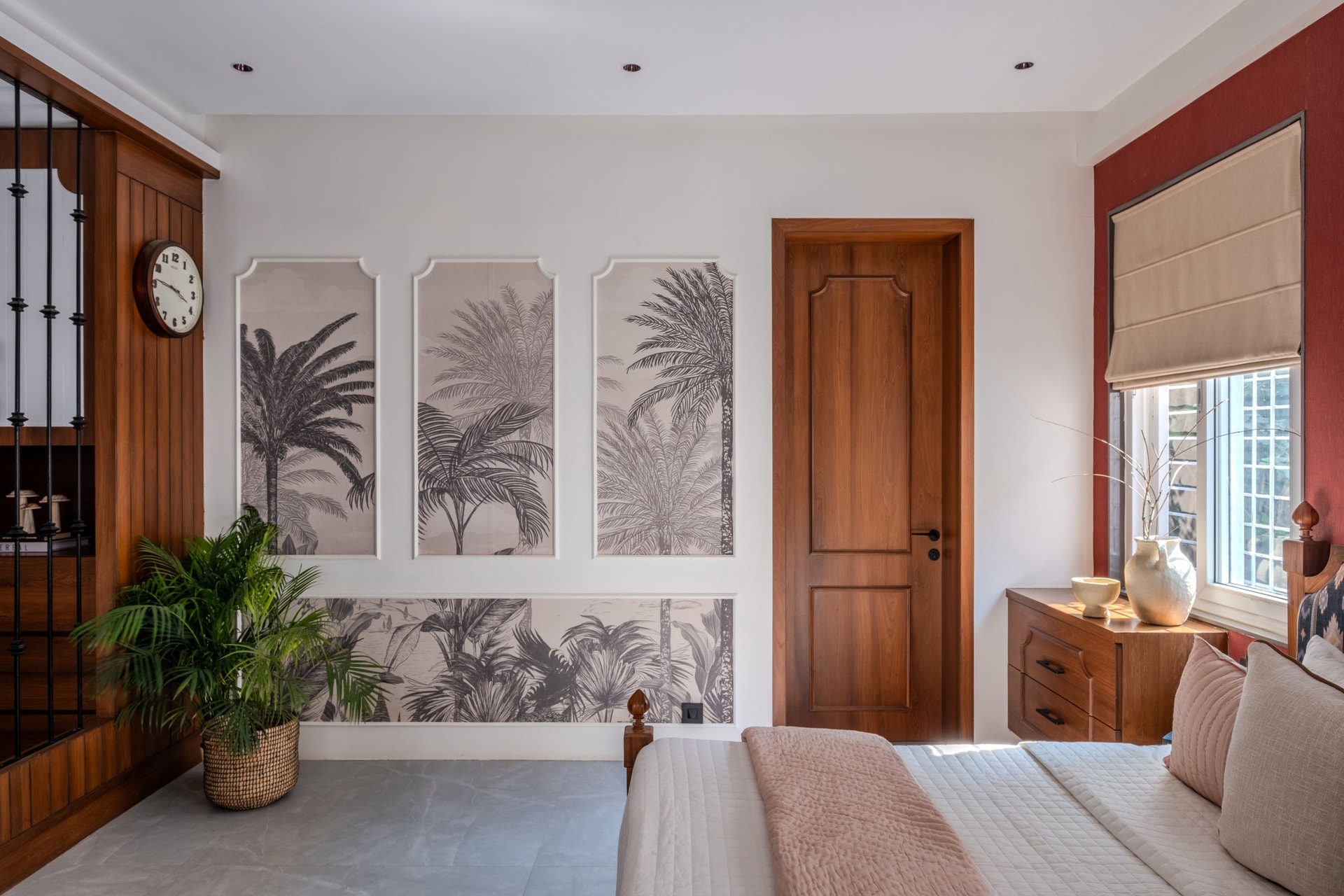 The master bedroom, where framed tropical wallpaper panels sit against a deep red accent wall