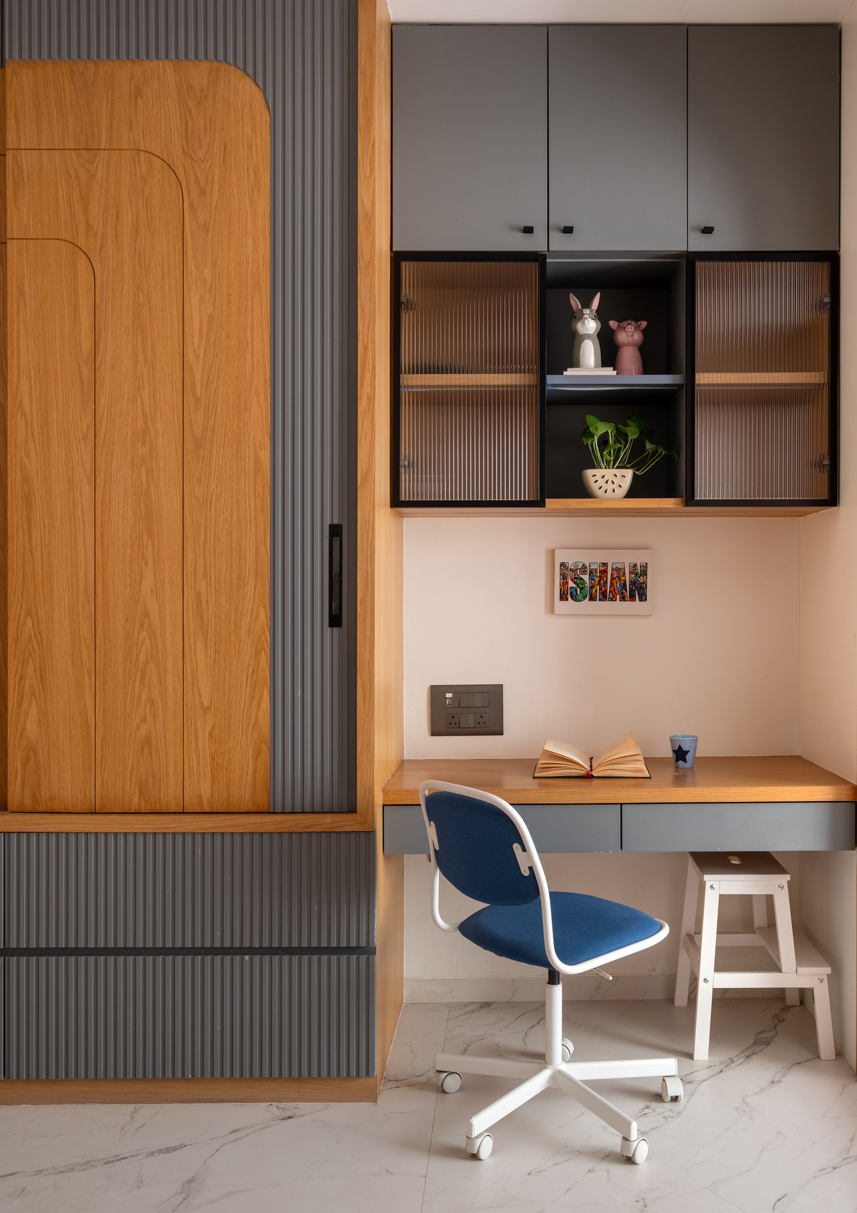 The desk wall in the children's room, where warm oak joinery meets grey fluted panels and reeded glass