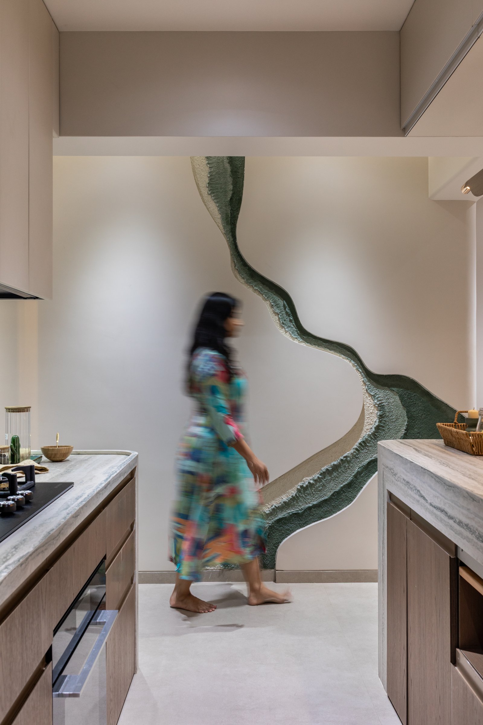The passage, where the green mural in raised mineral texture turns circulation into an event