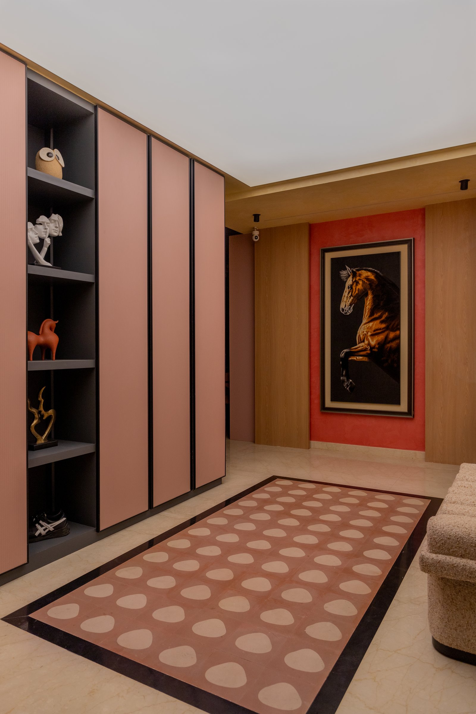 The foyer, where a dusty-pink storage wall and a terracotta-grounded equestrian artwork set the home's material palette