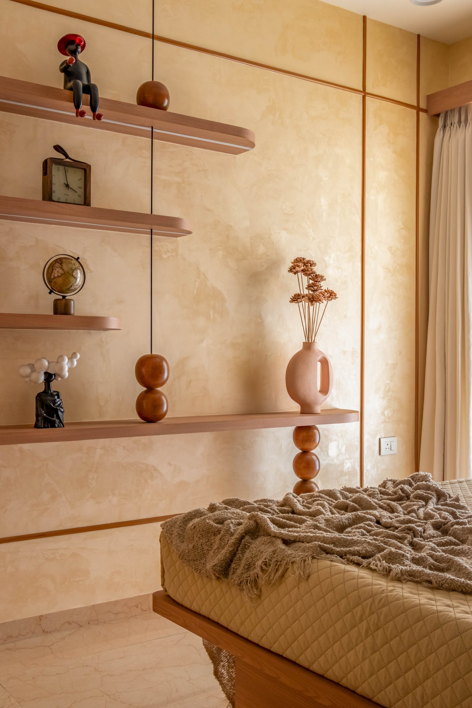 Asymmetric floating shelves do the work of a dresser, punctuated by curated sculptural objects against limewashed walls