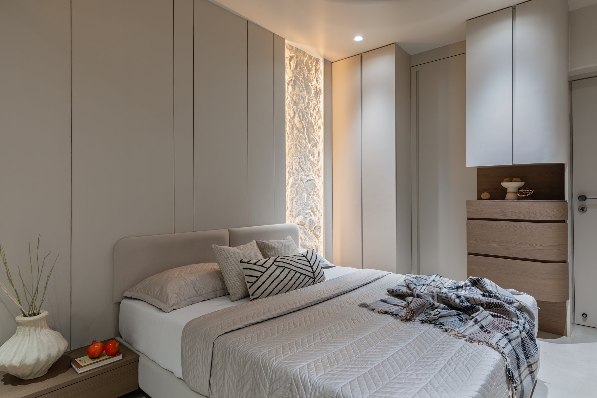 The parents' bedroom, where a slot of backlit rough plaster brings geological grain into a room of smooth planes