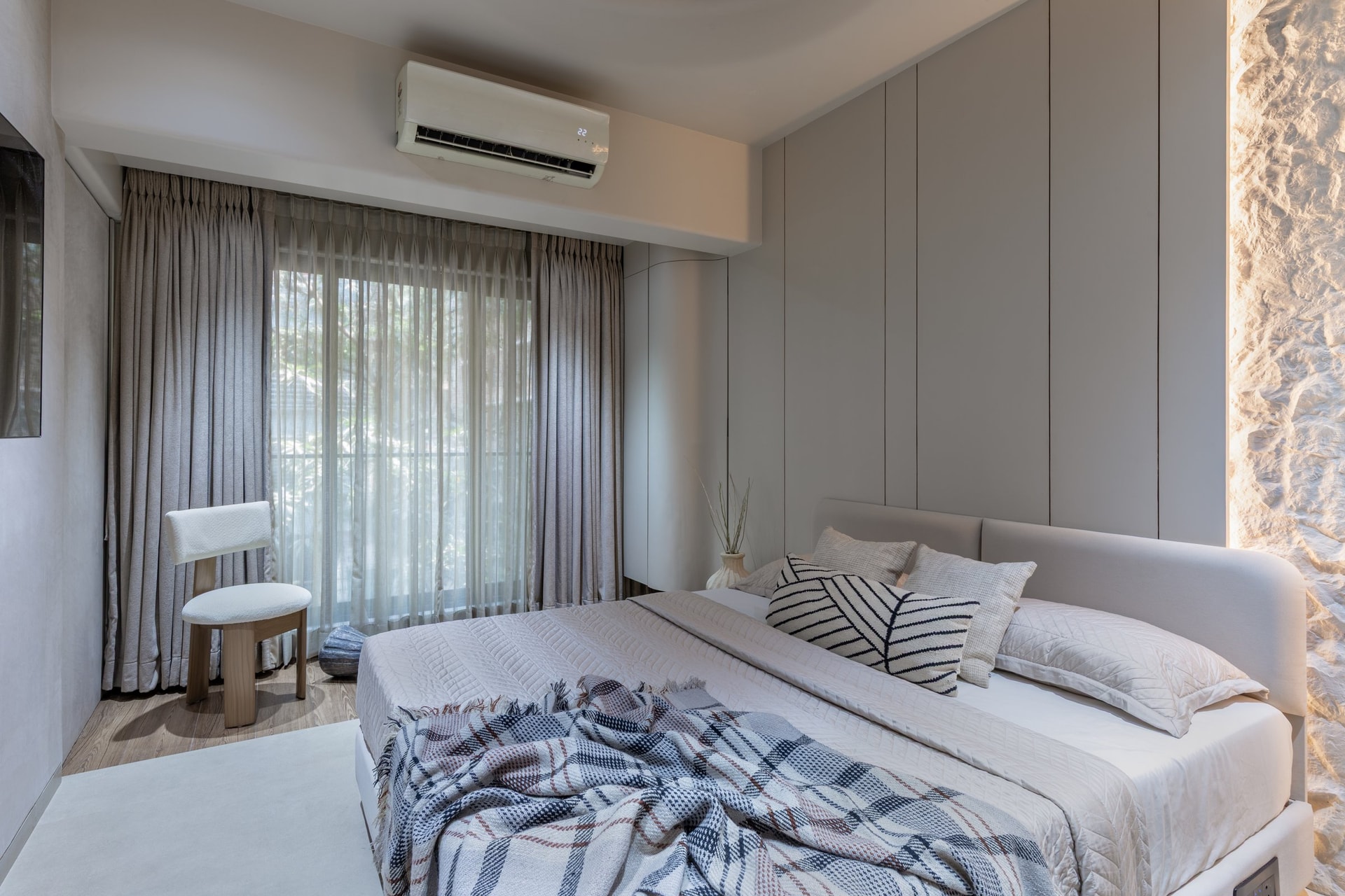 The absorbed balcony, extending usable floor area with a bouclé reading chair beside the sheer-curtained opening