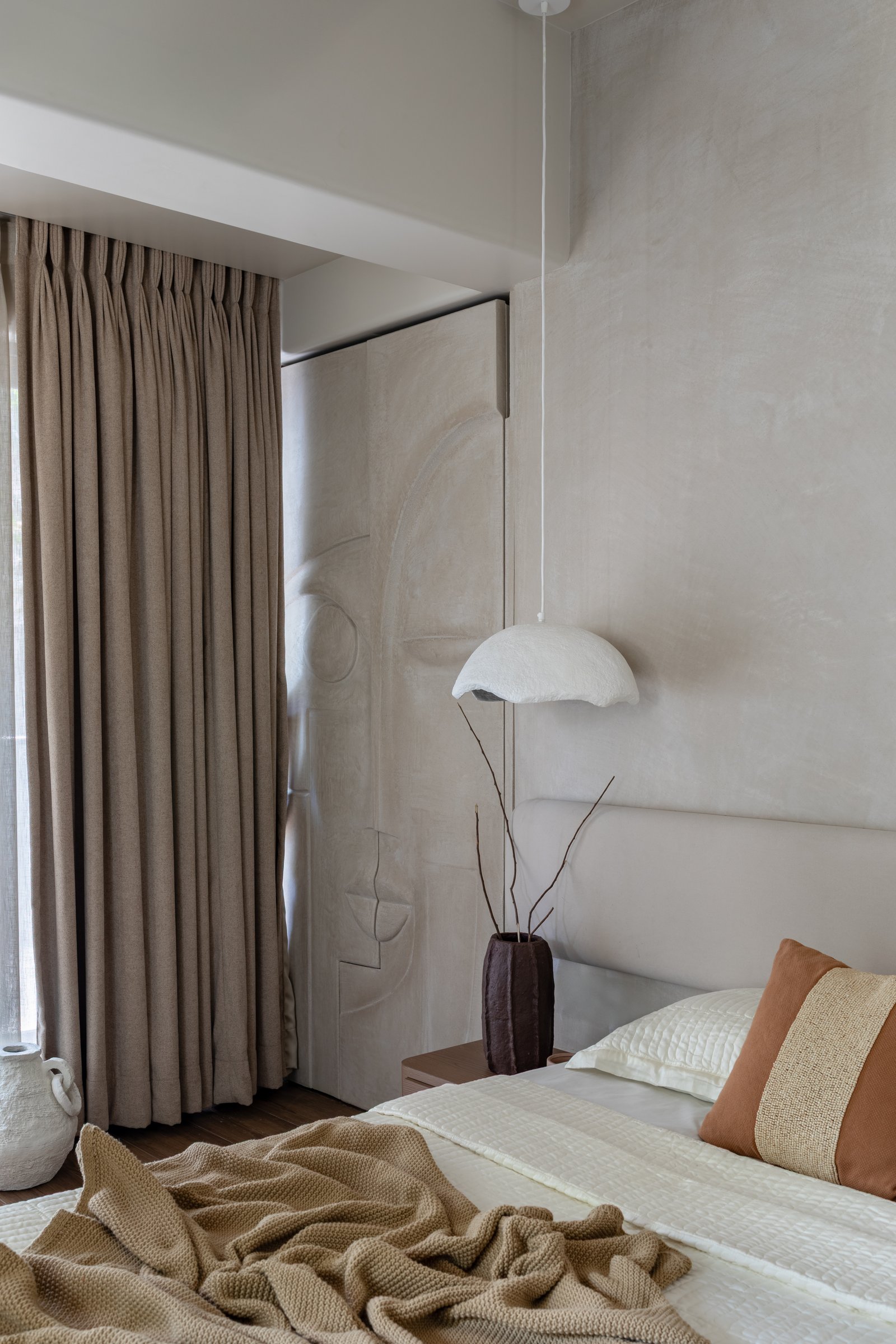 The headboard wall, its low-relief sculpted panel rendered in shallow bas-relief in pale plaster
