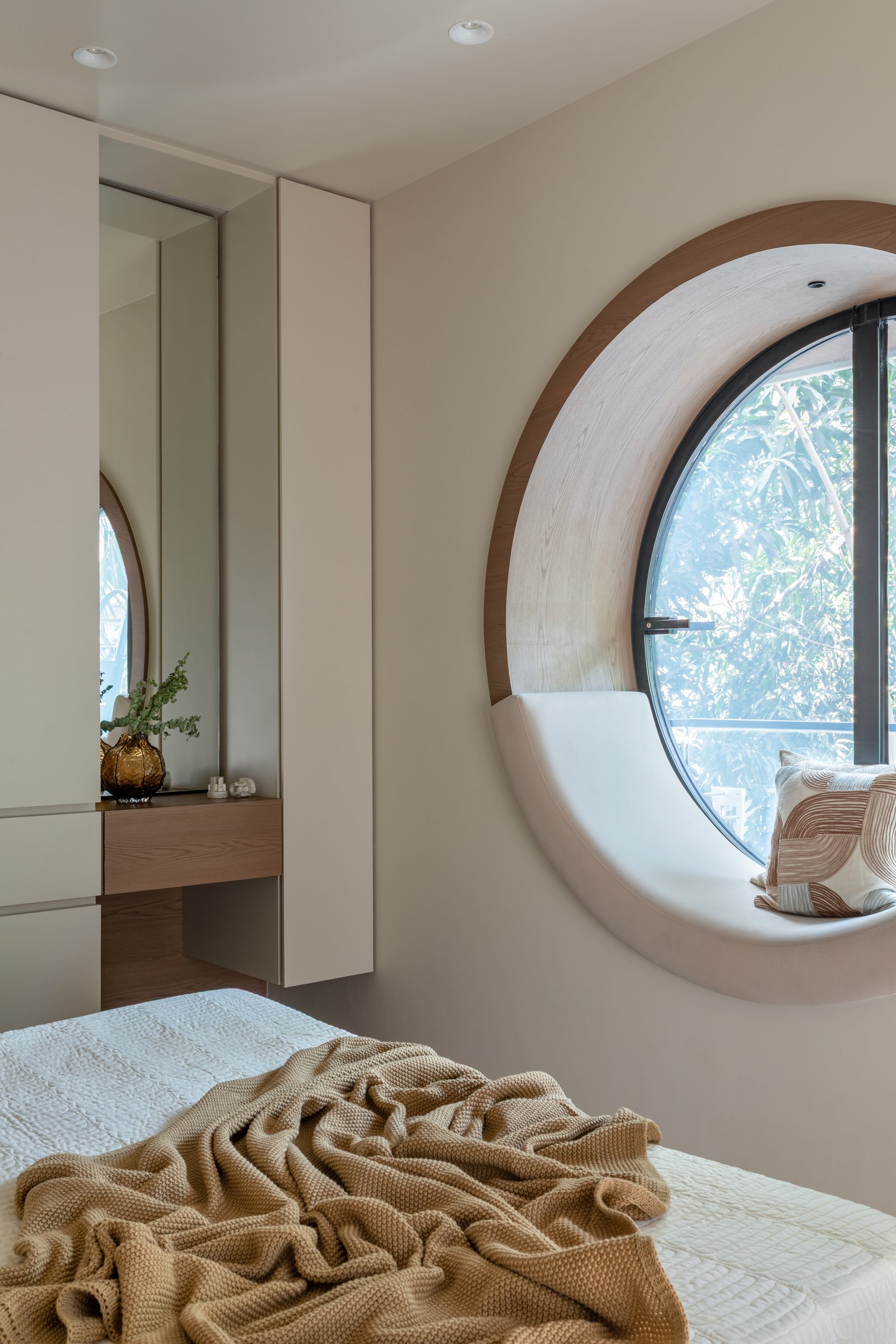 The dressing station opposite the round window, its floating shelf inset within a mirrored recess