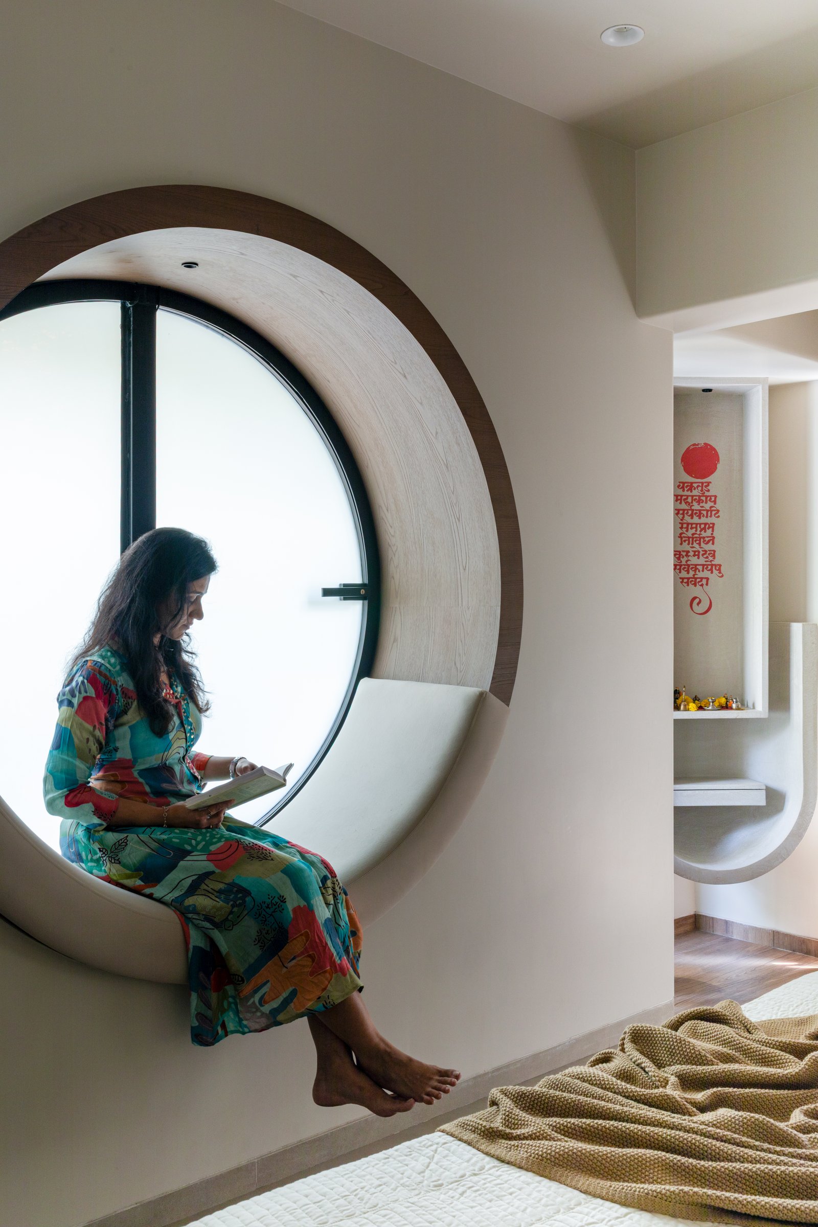 The reading nook in use, framing a view of the pooja niche across the passage