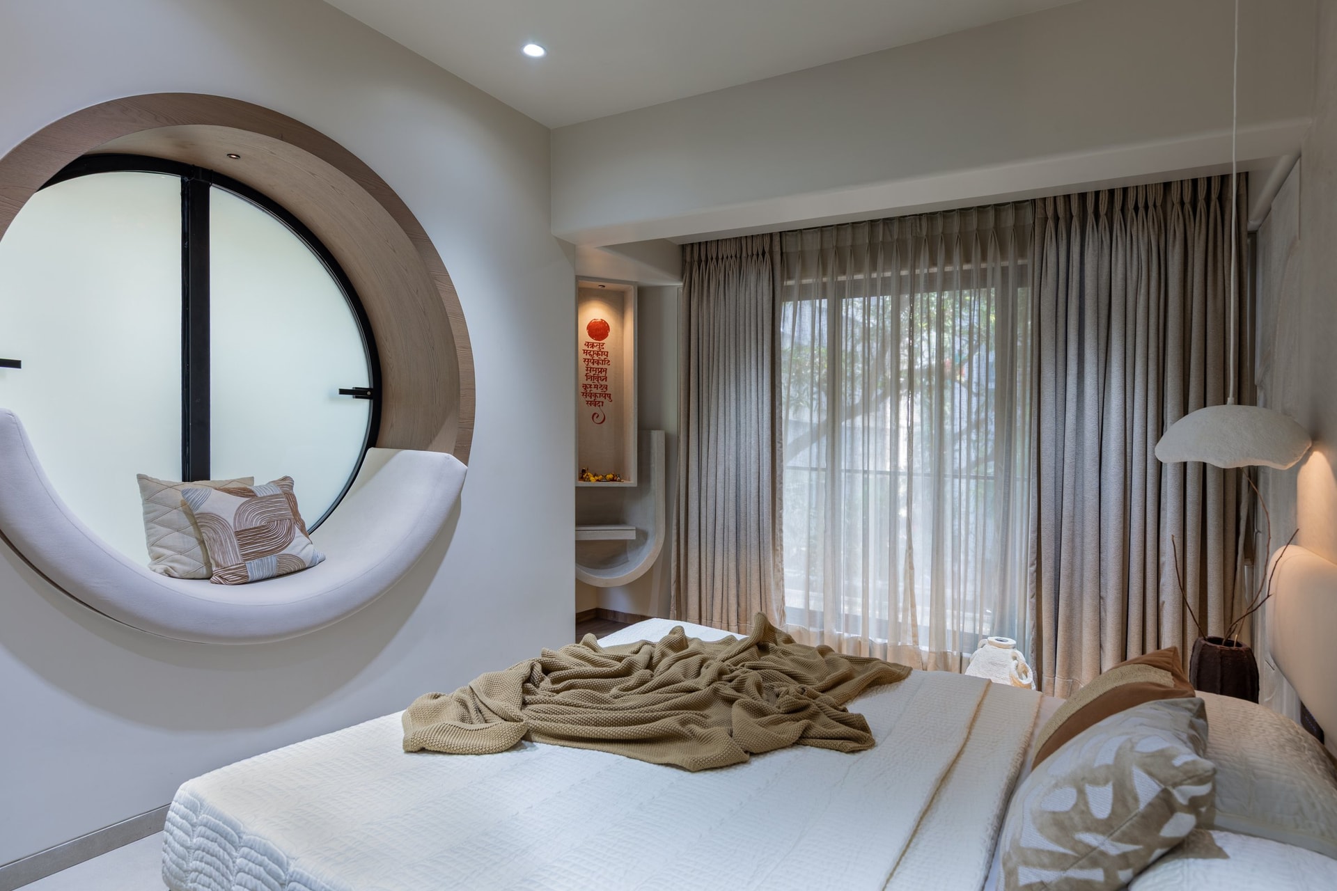 The circular window, its warm timber frame lined with a cushioned window seat that curves along the lower half of the aperture