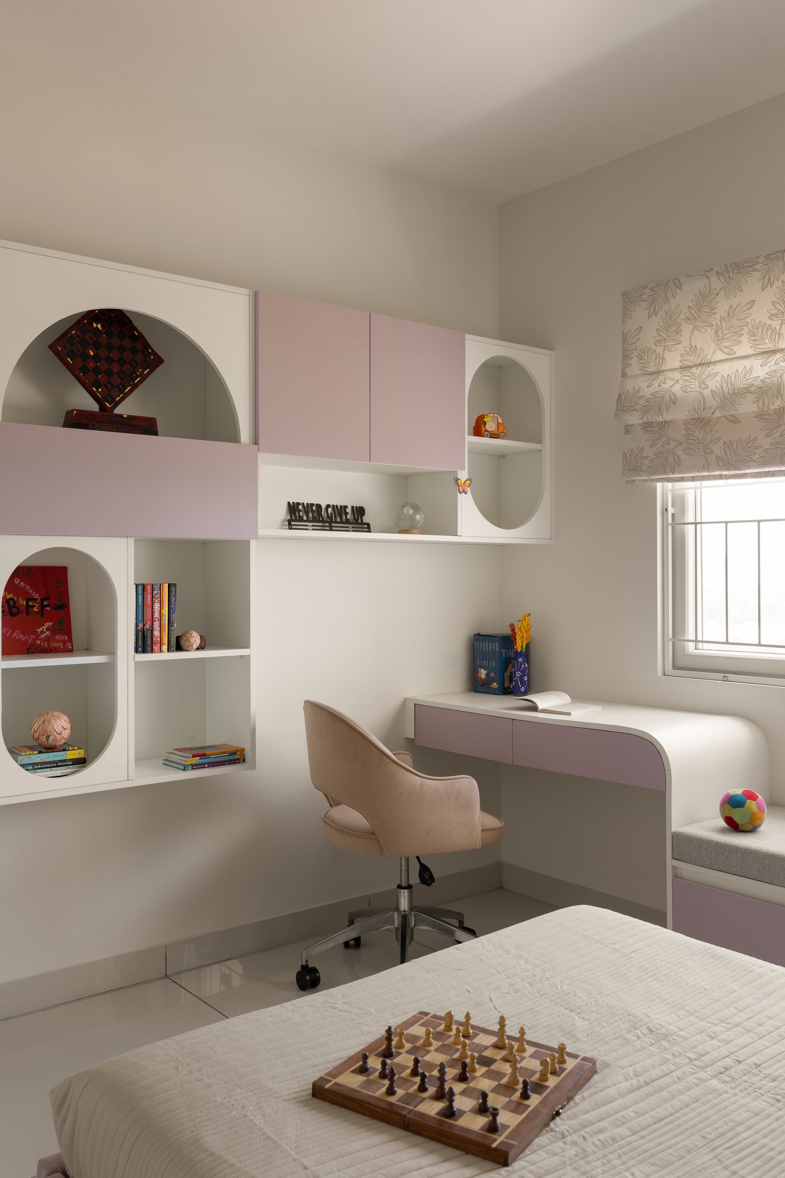 The study corner in the daughter's room, with its lavender-fronted desk, cushioned window seat, and composition of arched and rectangular open niches
