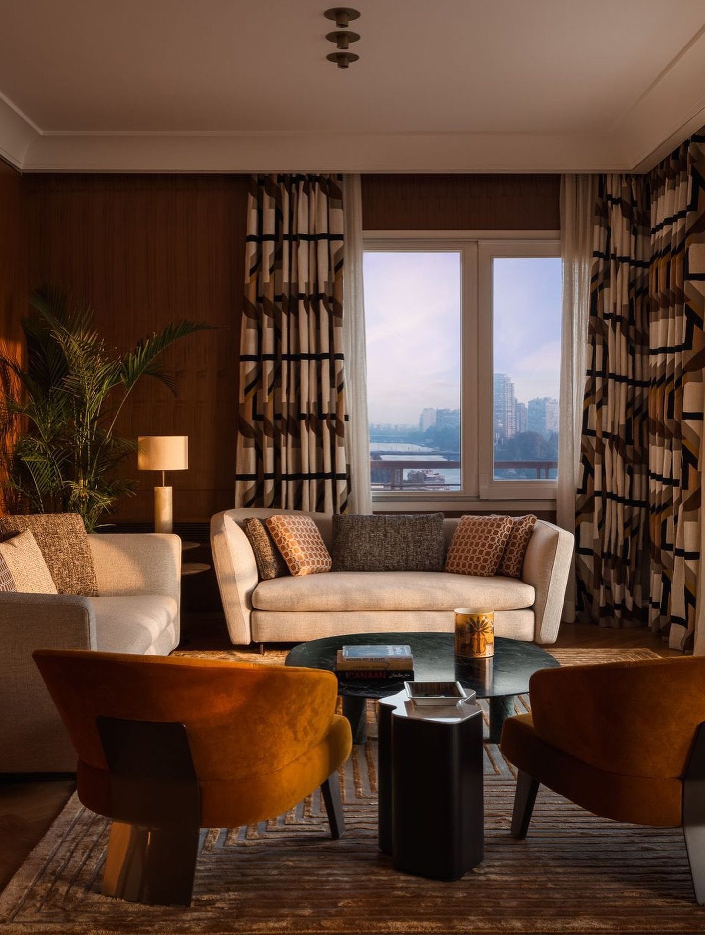 Burnt-orange velvet and graphic curtains frame the Nile view at dusk.