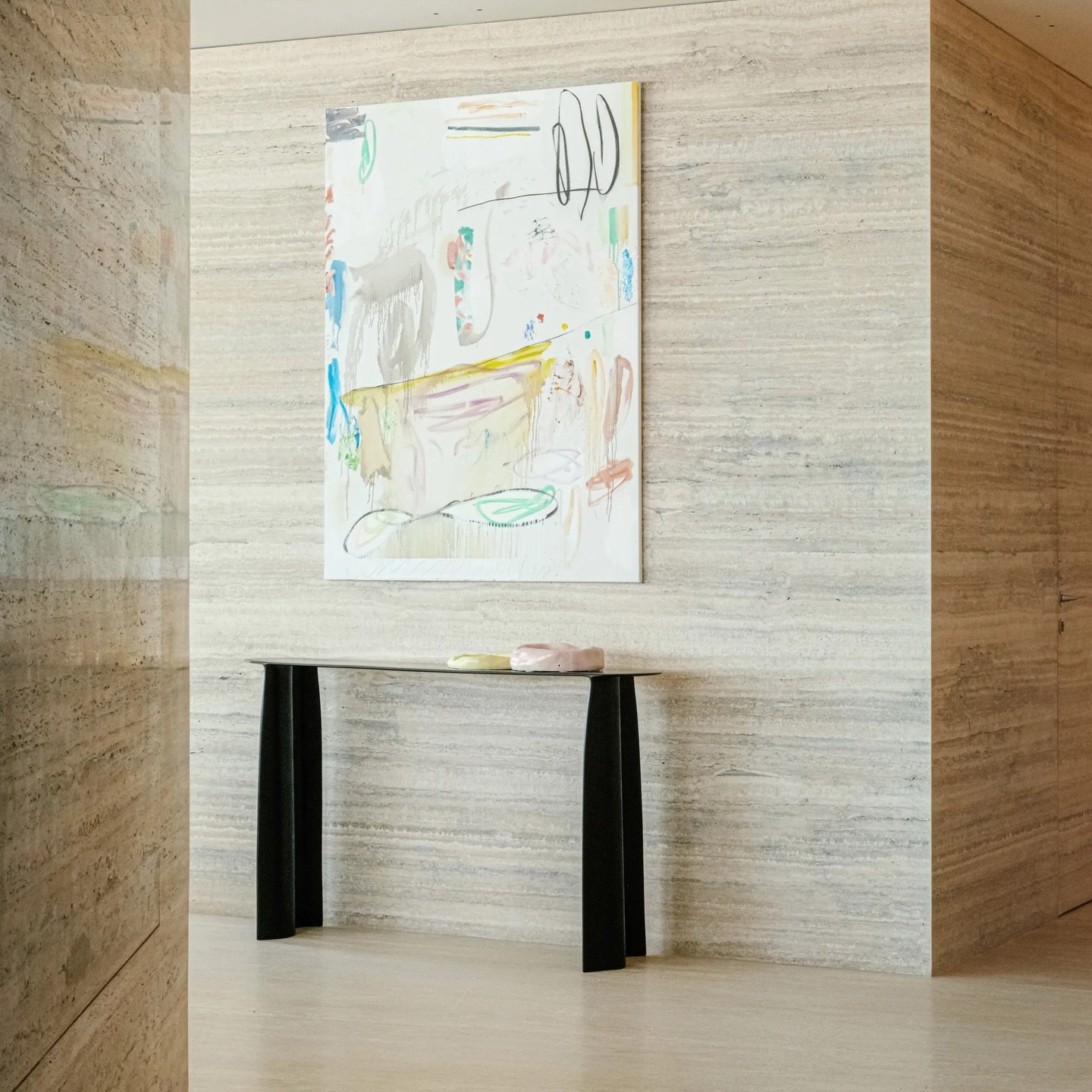 The foyer, lined in book-matched stone, offers a restrained threshold marked by a single abstract painting.