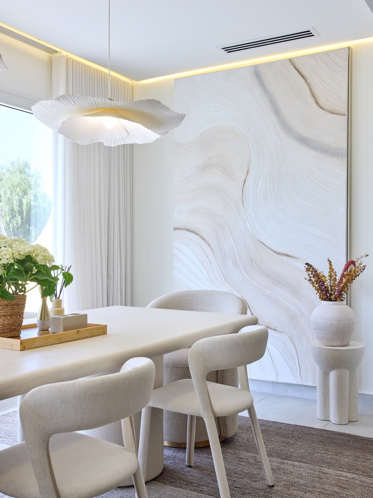 The dining nook, composed around a stone-topped table and a floor-to-ceiling tonal artwork.