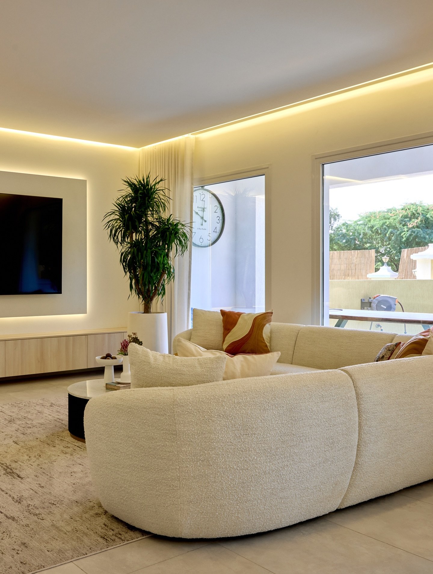 The living area, where a curved boucle sectional softens the architecture's linear geometry.