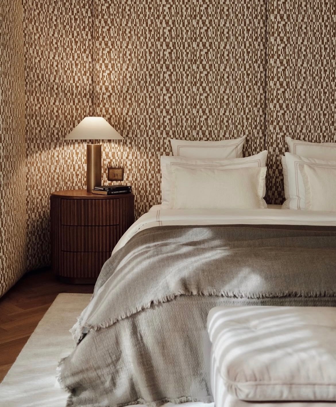 A fluted nightstand and upholstered wall bring the same restraint into the private quarters.