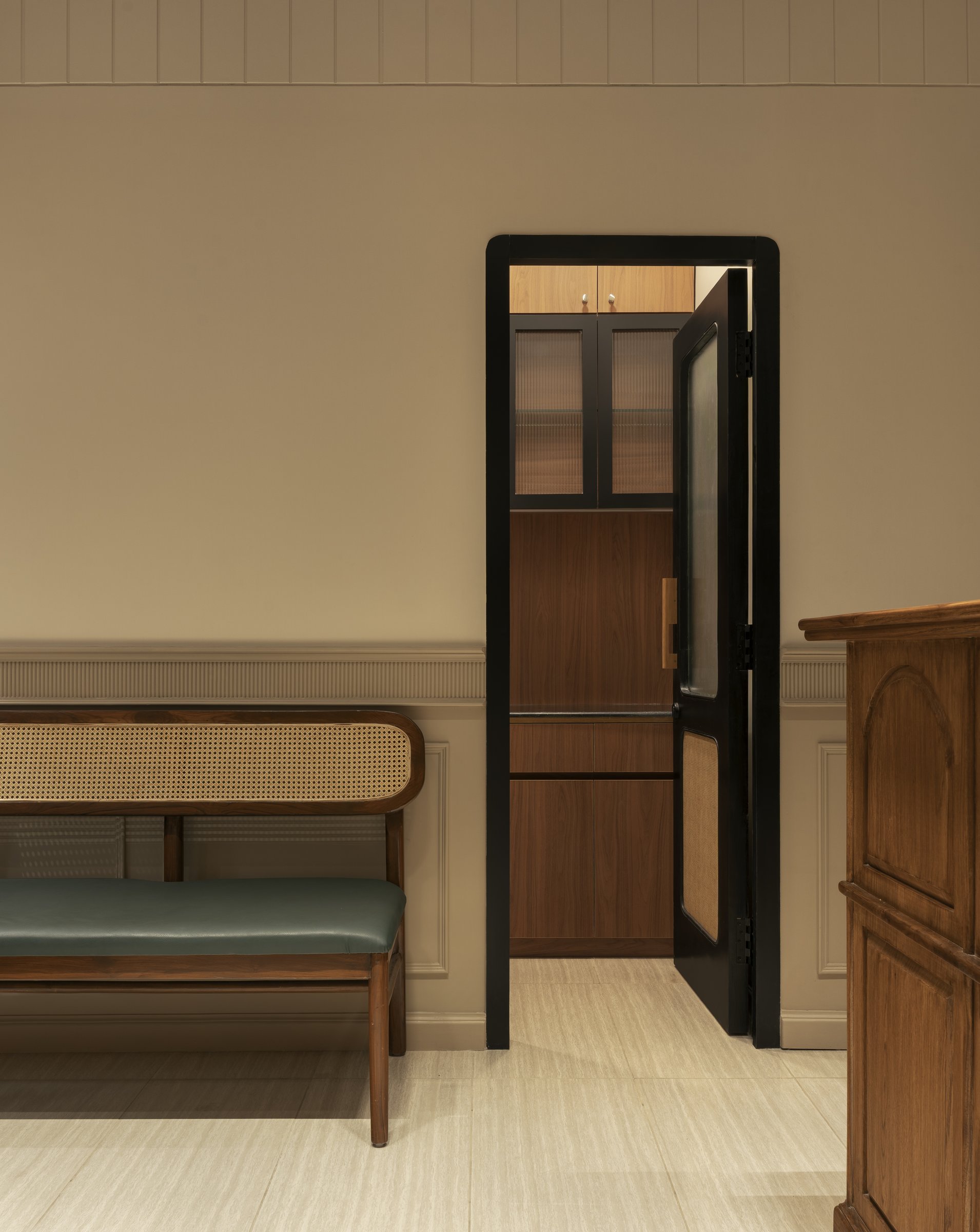 A view through the interior threshold, where a slim tallboy in reeded glass and warm wood punctuates the passage