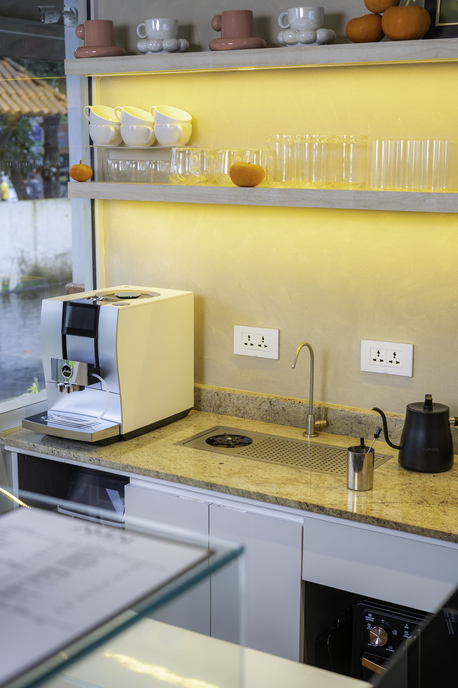 The working edge, where a speckled stone worktop meets a warm-toned plaster back wall under floating shelves