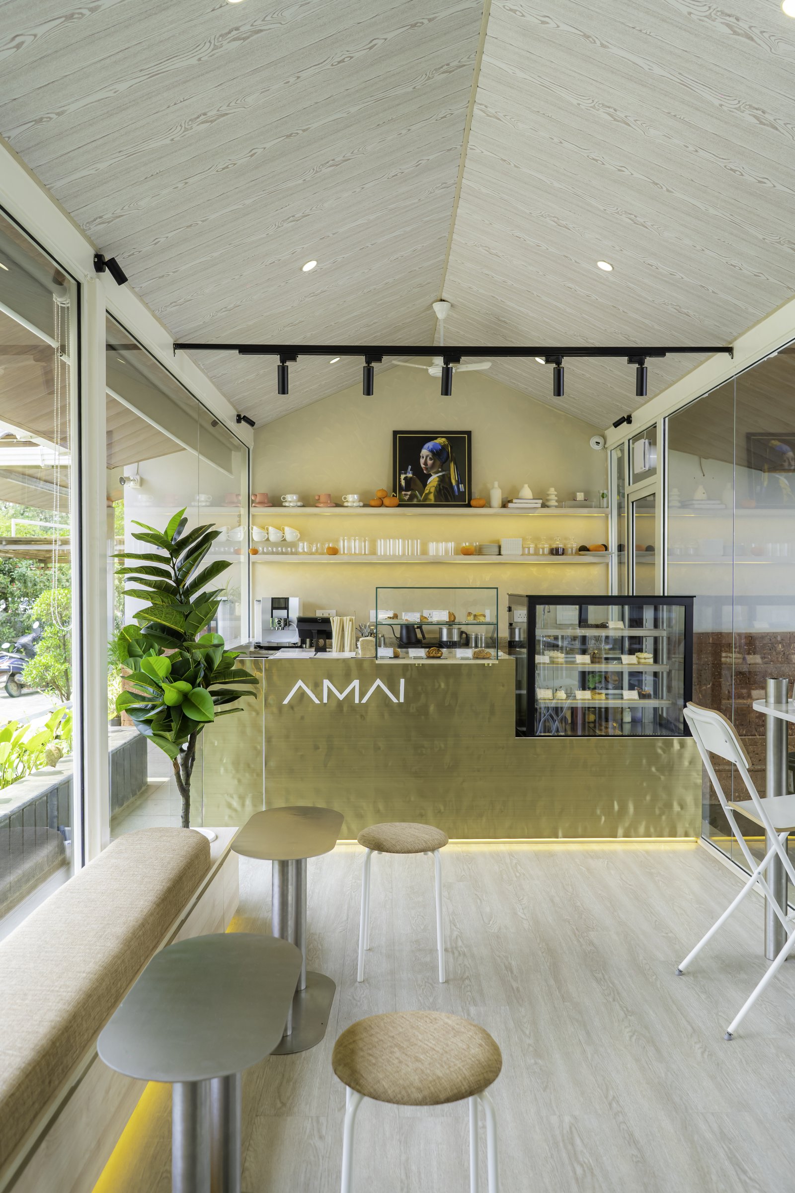 The main volume, where a pale wood pitched ceiling and a hammered-brass counter set the room's terms