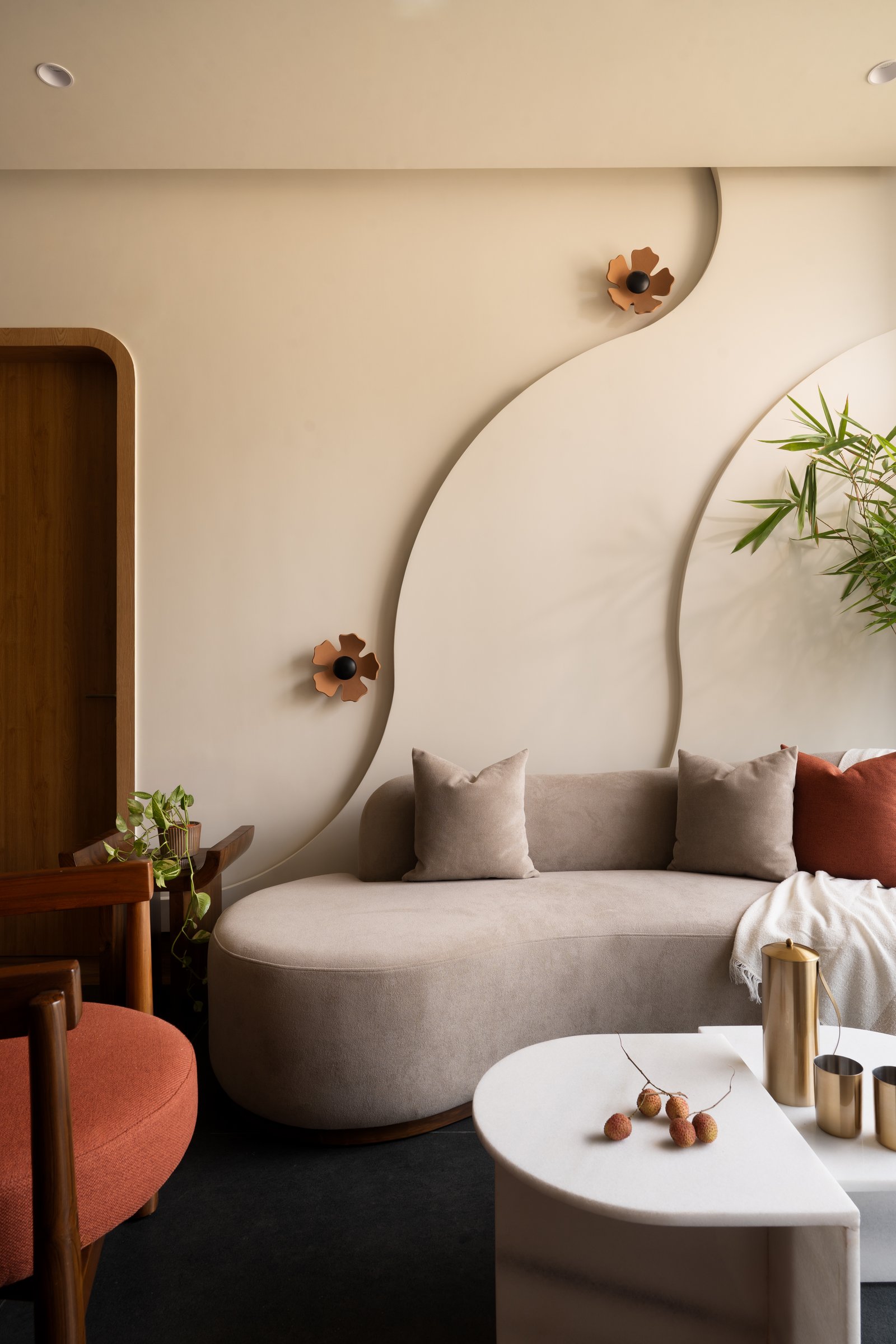 The seating corner, its curved sofa and copper-toned floral wall lights softening the compact volume