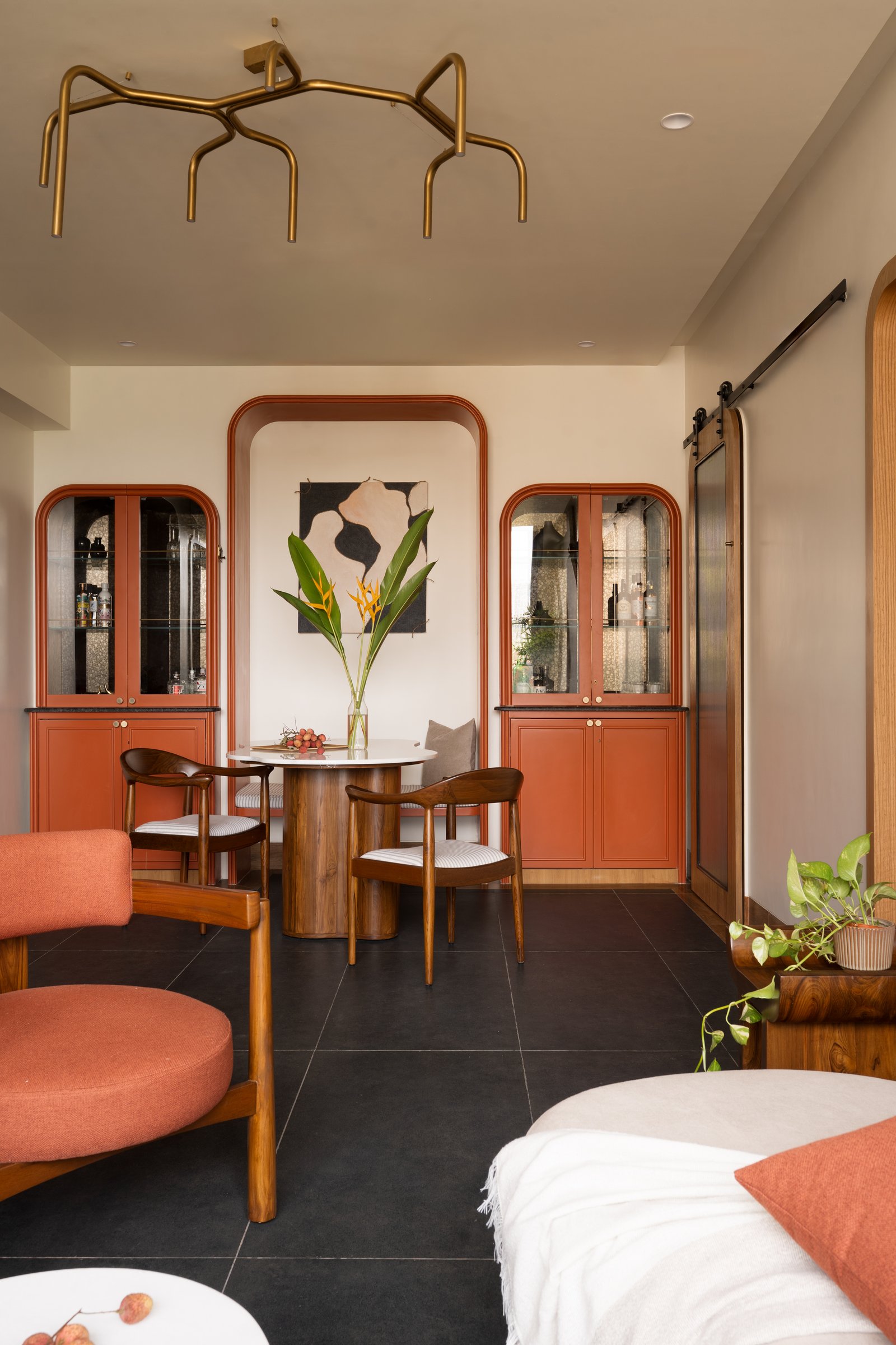 The dining area seen from the living room, where symmetrical terracotta cabinetry frames the artwork niche