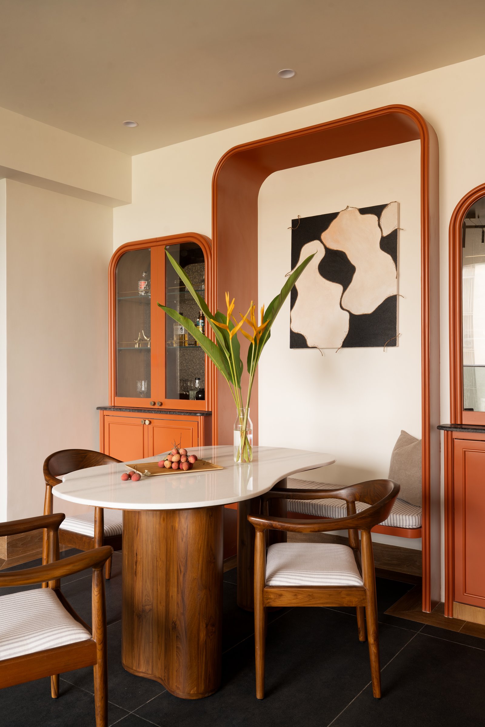 The dining niche, framed by a tall terracotta outline that holds an abstract artwork above a tucked banquette