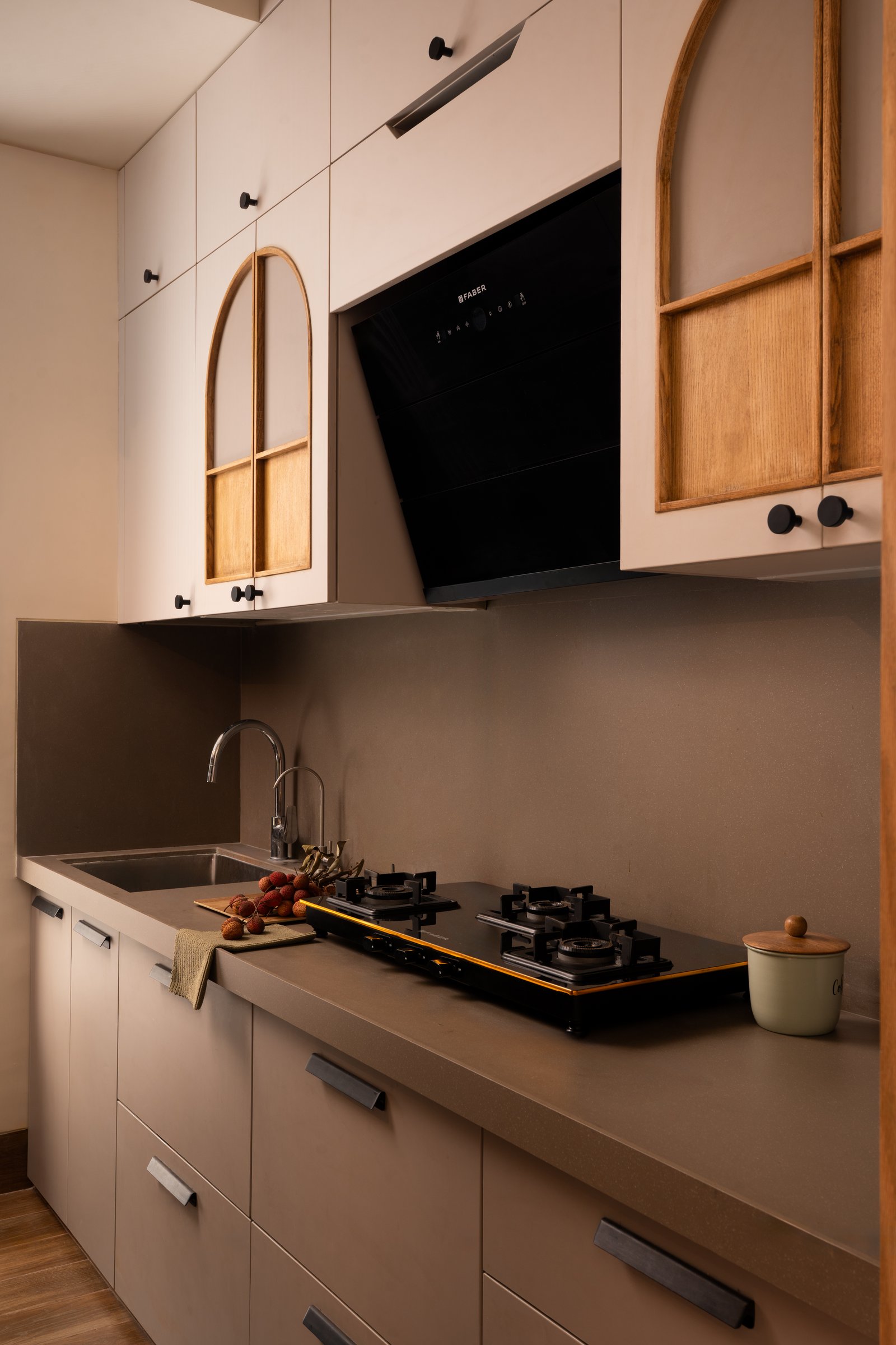 The kitchen, where arched glazed upper cabinets echo the dining niche in a softer tonal register