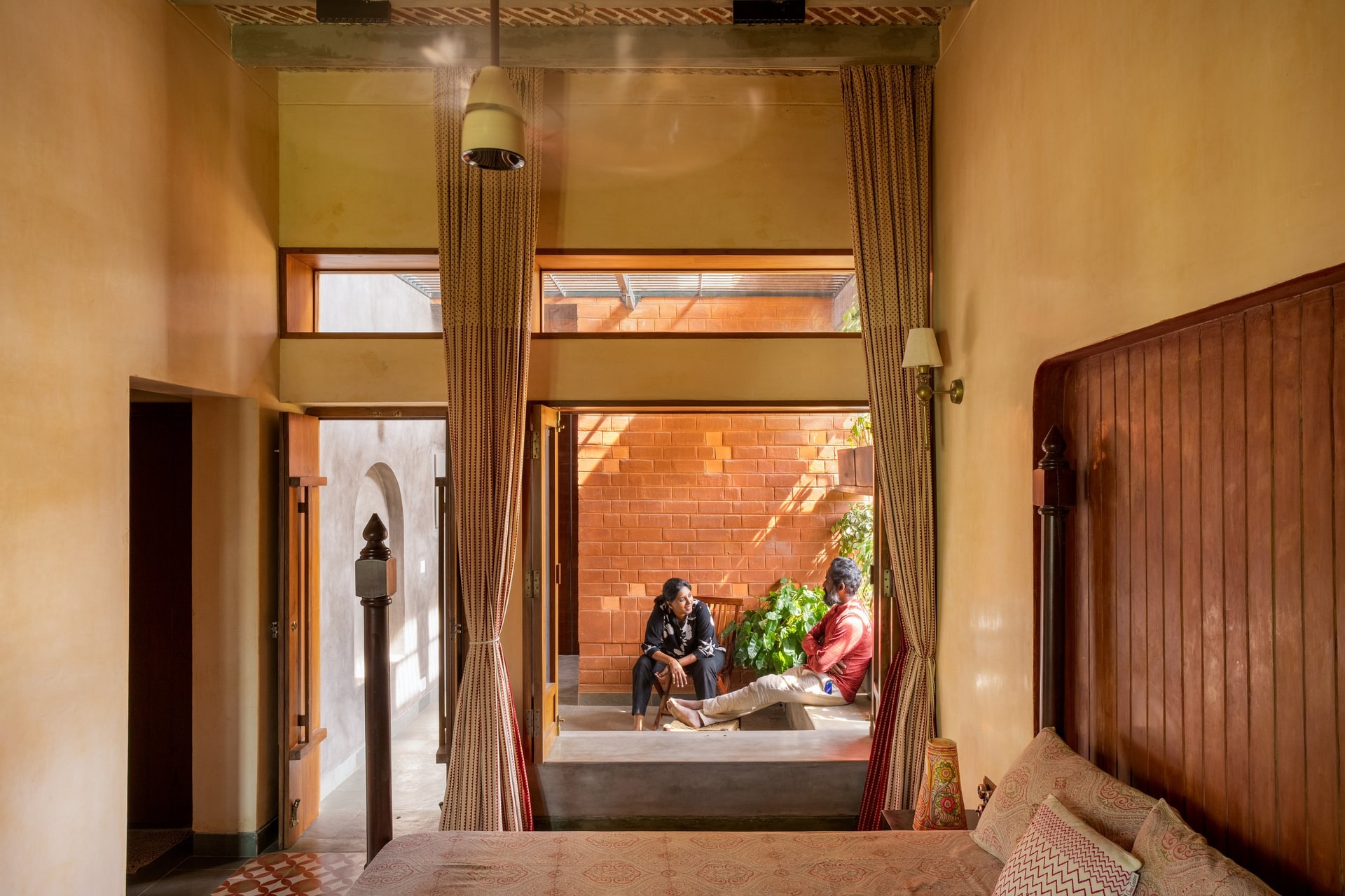 A bedroom opens directly onto a small private courtyard through a curtained timber threshold