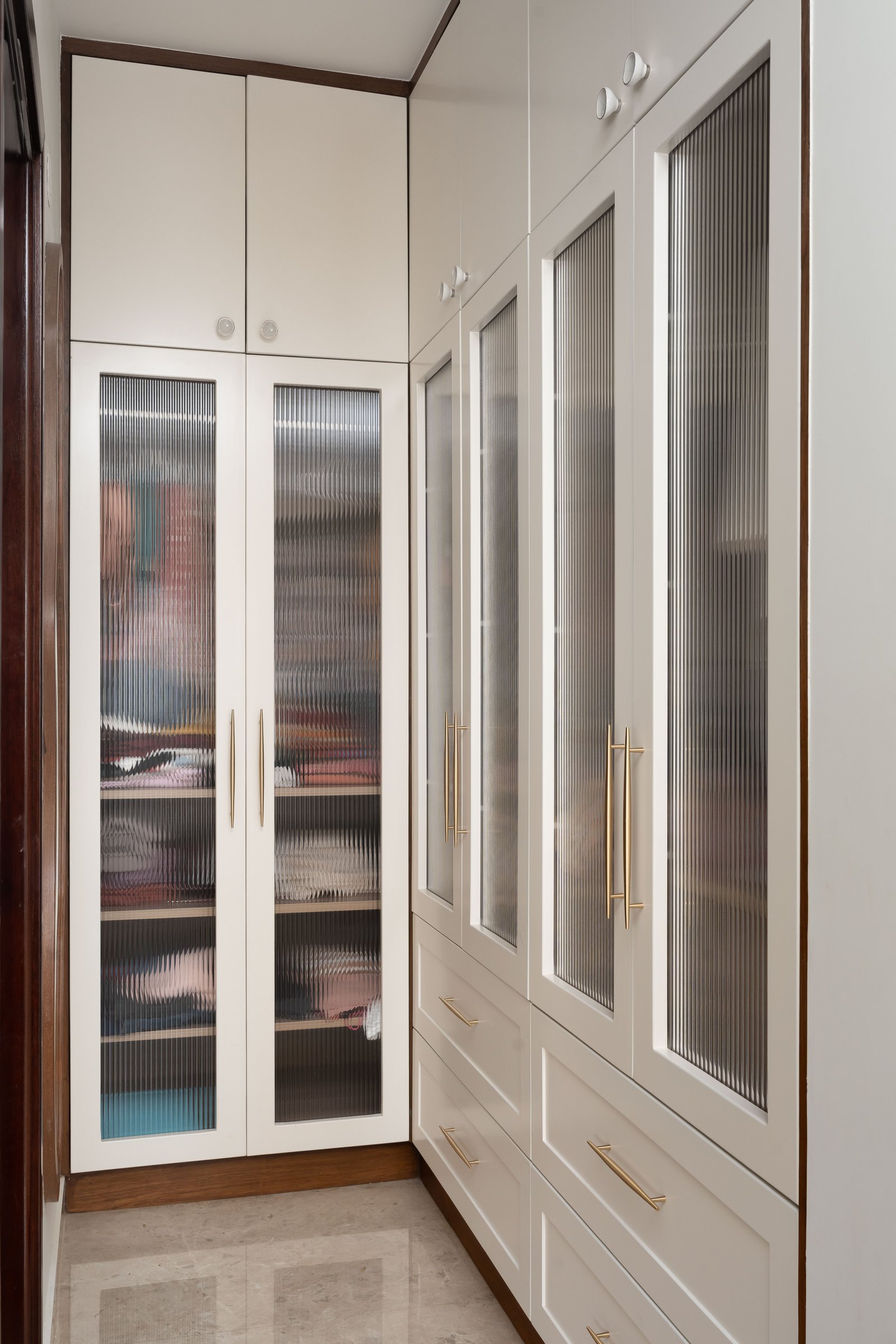 The dressing corridor, where reeded glass and brass pulls extend the suite's classical grammar