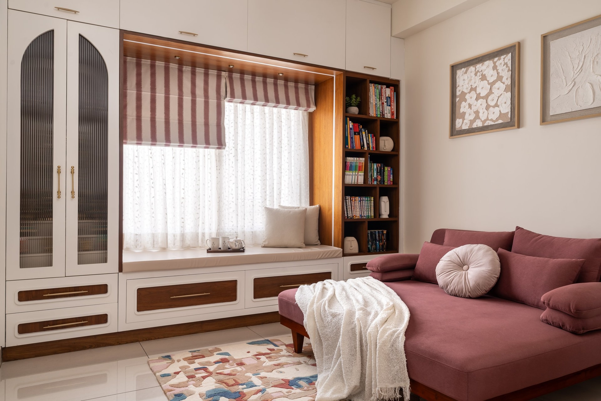 The reading nook, where a dusty-rose daybed faces a built-in window seat and open bookshelf
