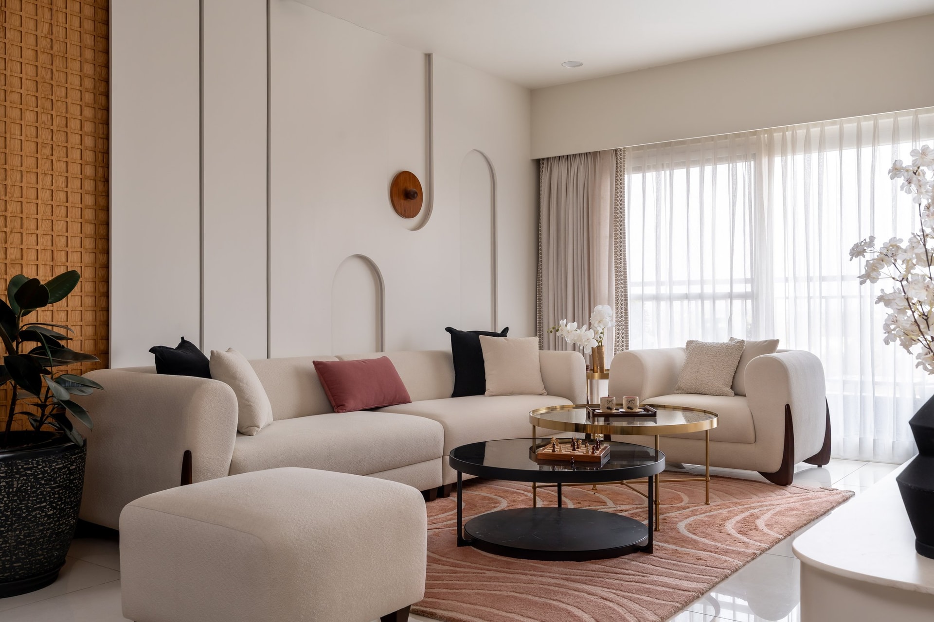 The living room, anchored by a curved bouclé sectional set against panelled ivory and a woven wood-toned wall