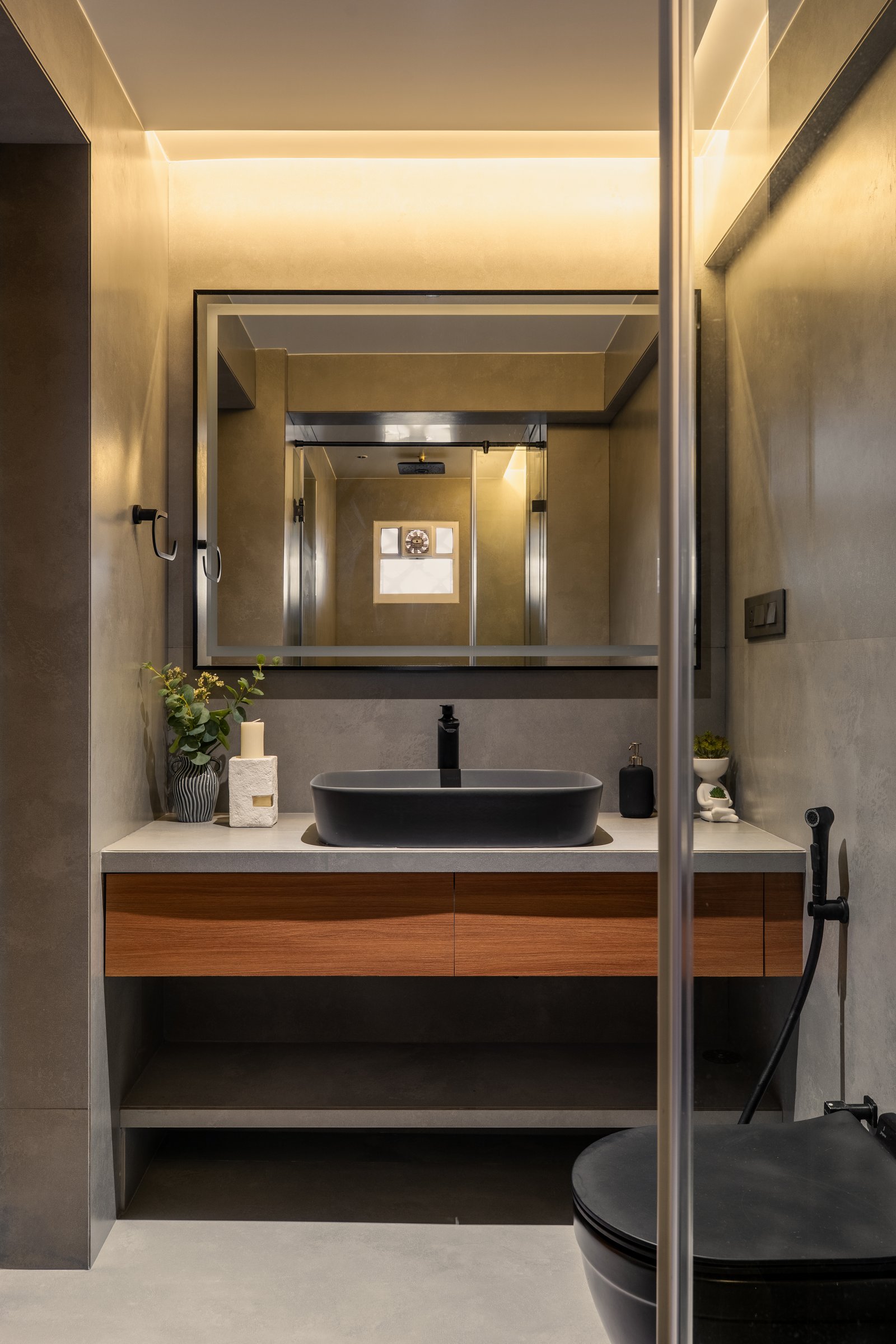 The powder room, where micro-cement walls in muted grey wrap a floating teak vanity and dark vessel basin