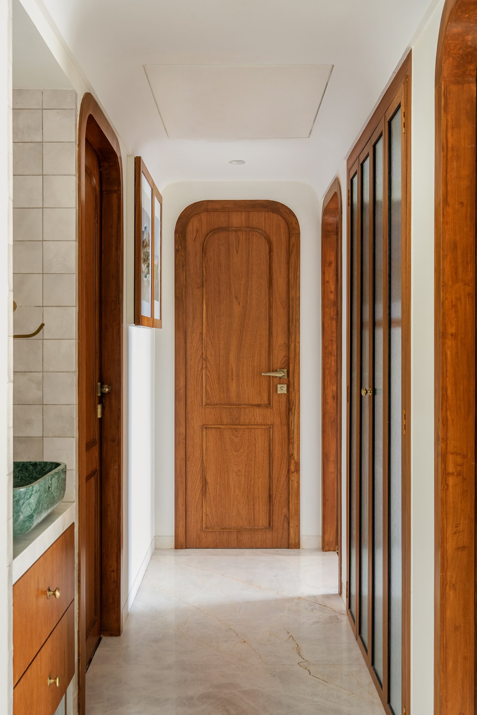 The passage between private rooms, where arched teak doorways soften the circulation