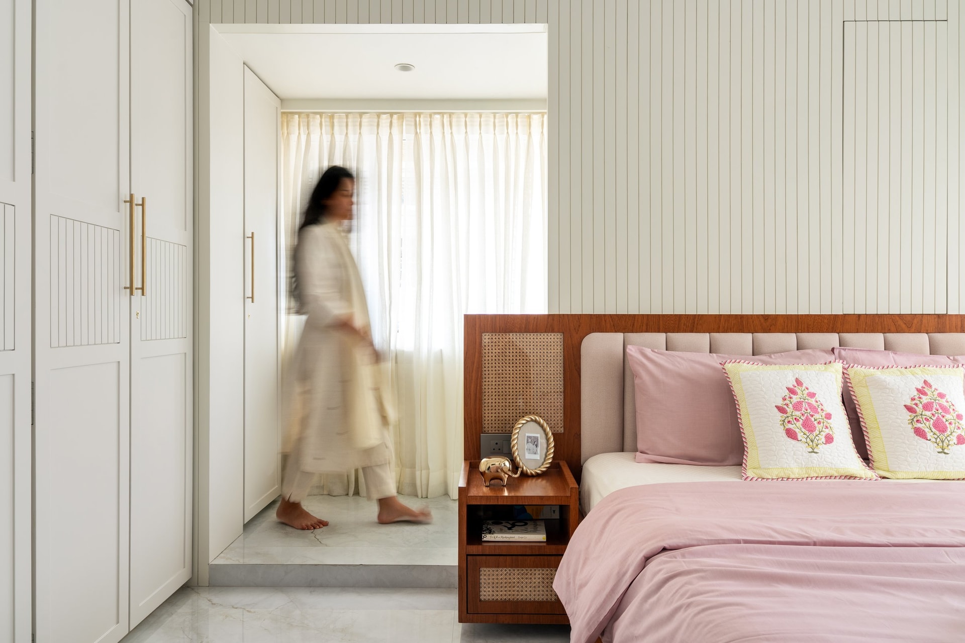 A cream fluted-and-panelled wardrobe anchors the opposite wall of the master bedroom