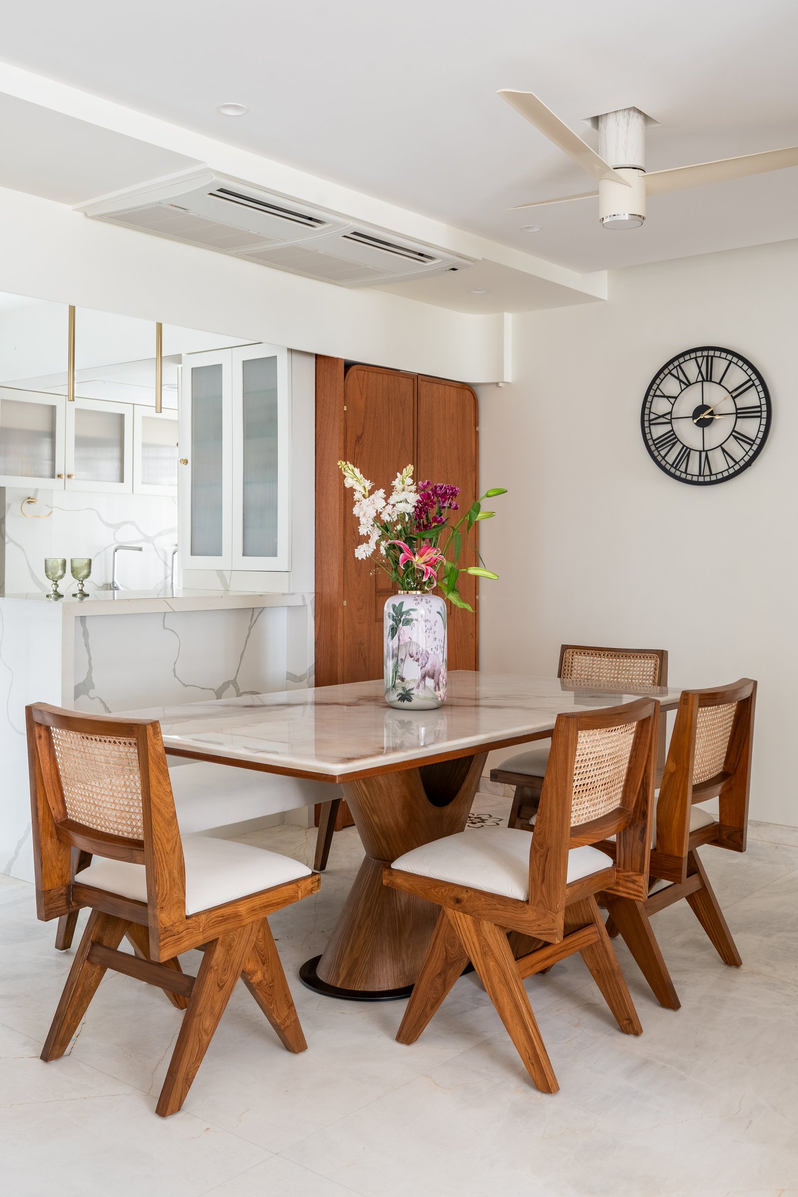 The dining table seen against a curved teak pooja cabinet that softens the corner