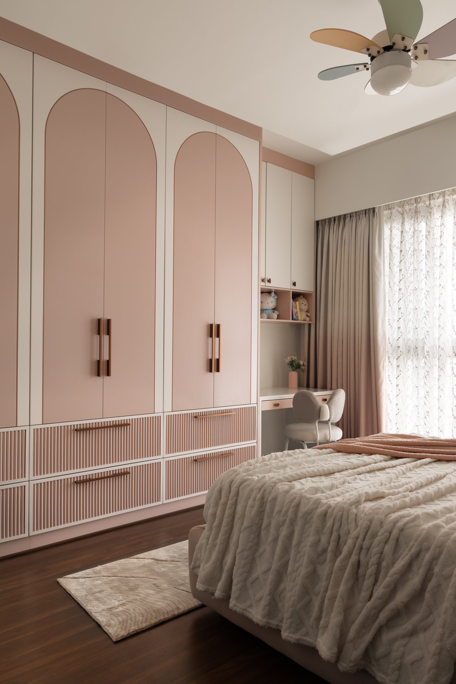 The daughters’ room, where dusty-rose arched wardrobes meet a compact study nook