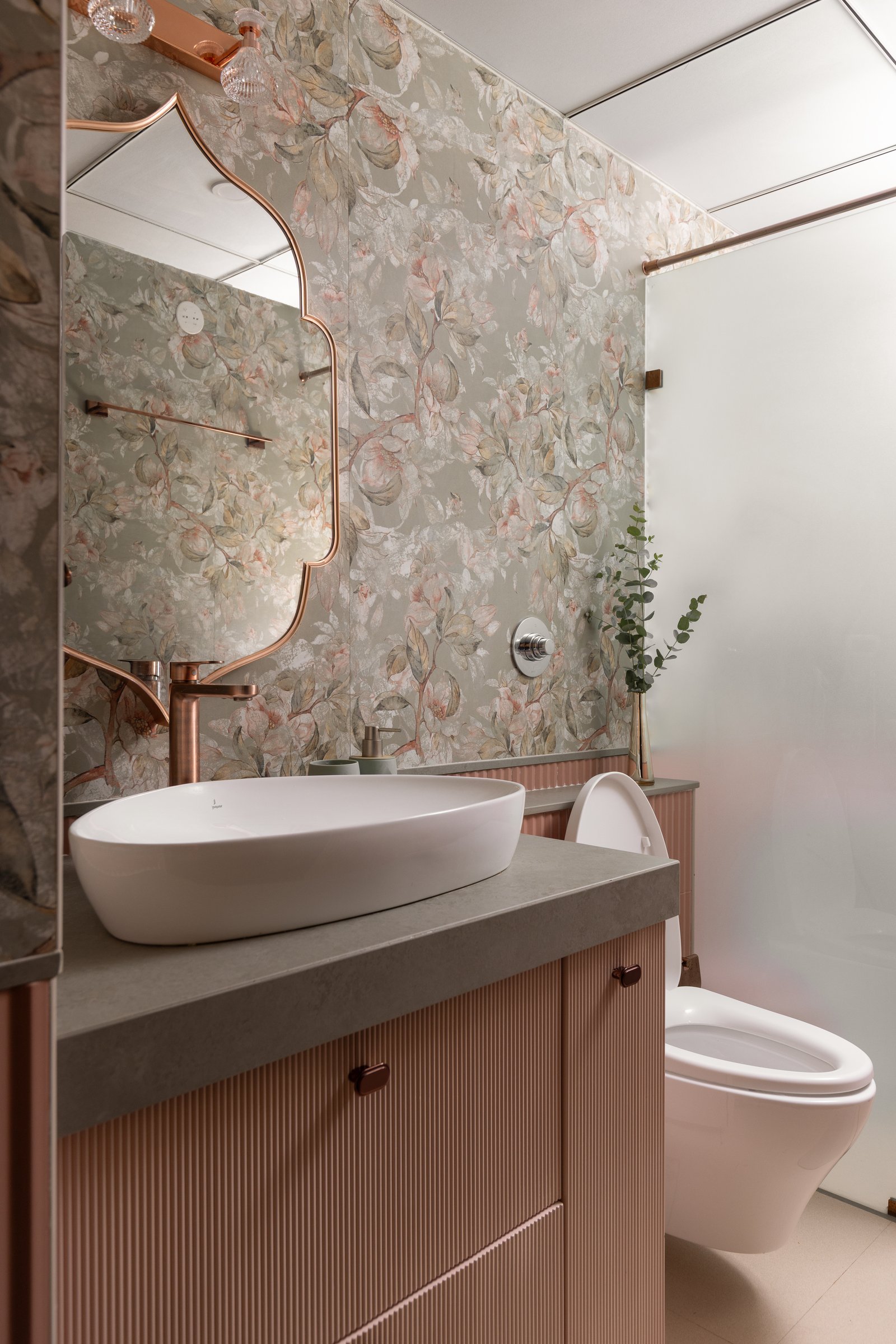 The daughters’ bathroom, where botanical wallpaper and a fluted pink vanity meet rose-gold tapware