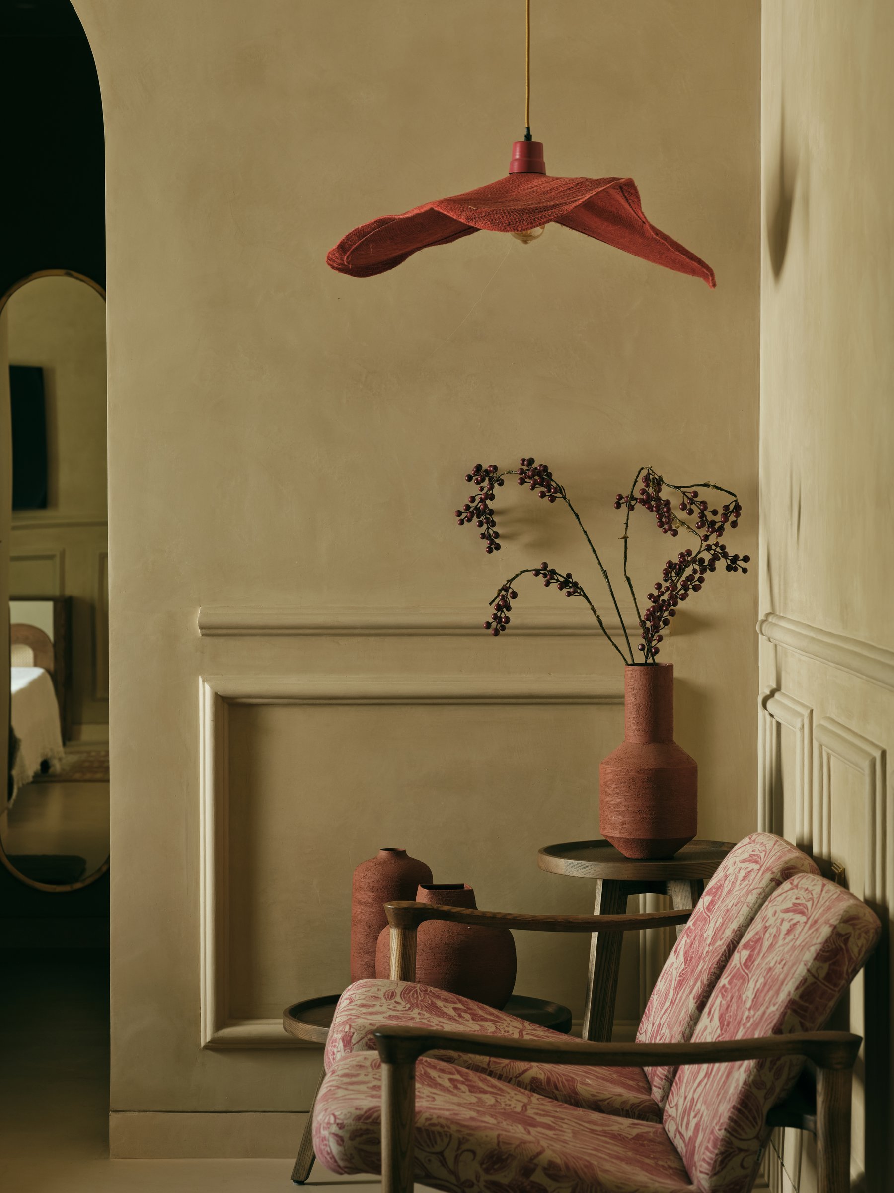 A vignette outside the guest bedroom, where terracotta vessels and a floral armchair carry the memory-collector sensibility