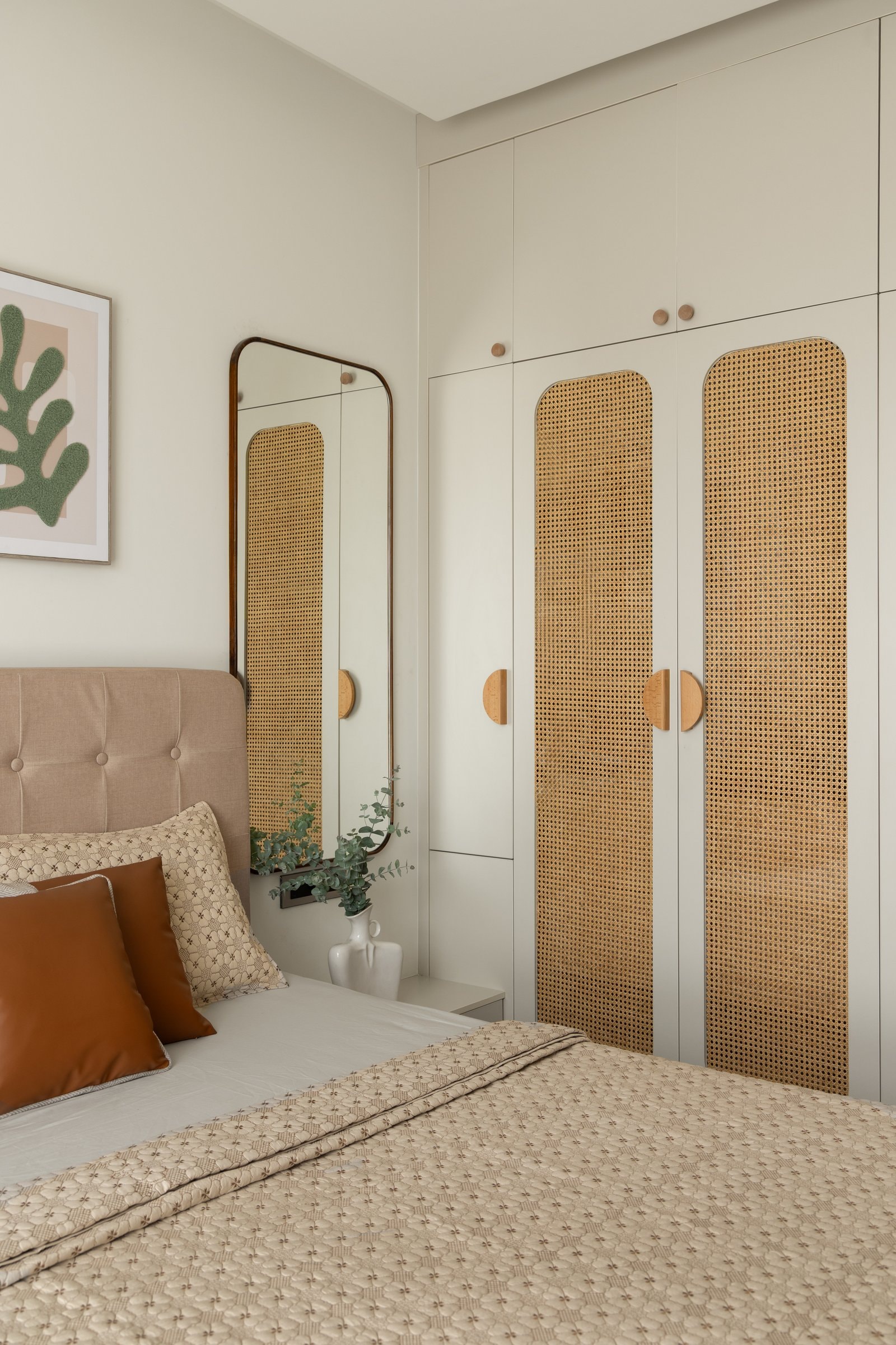 Cane-fronted wardrobes and a slim arched mirror extend the guest room’s sense of space
