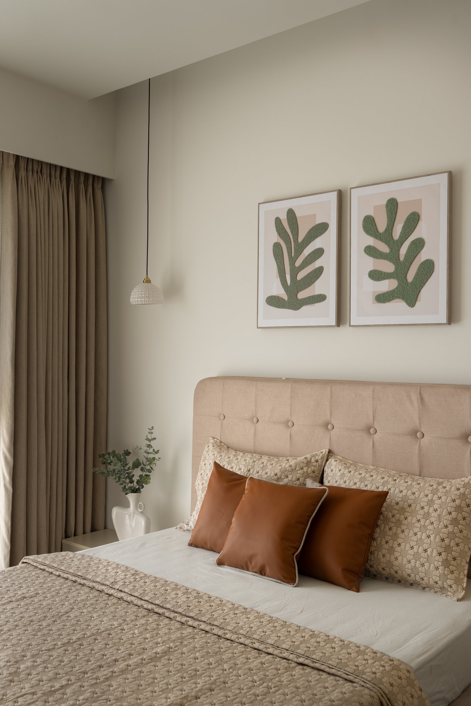 The guest bedroom, where botanical prints and tan leather cushions warm a light-toned palette
