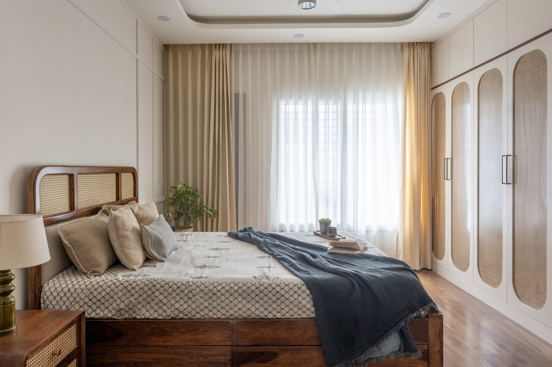 The bedroom, with a cane-inset timber bed beneath a curved recessed ceiling