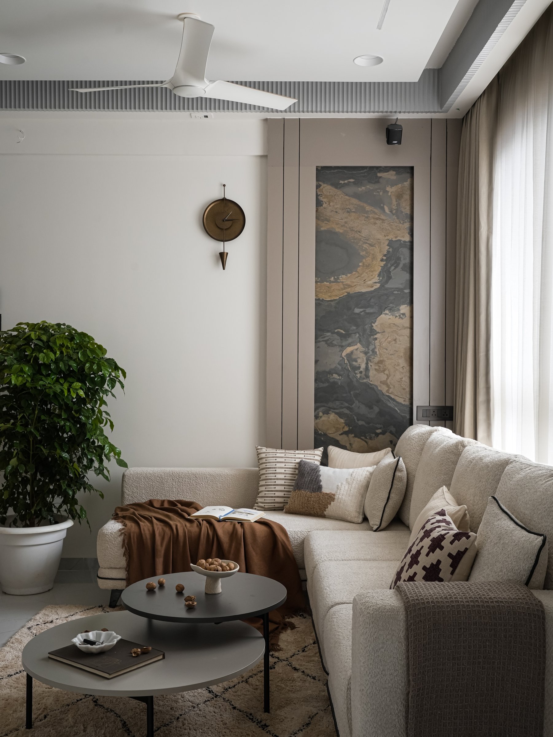Panelled taupe millwork, a fluted ceiling band, and paired graphite coffee tables calibrate the living room's restrained palette