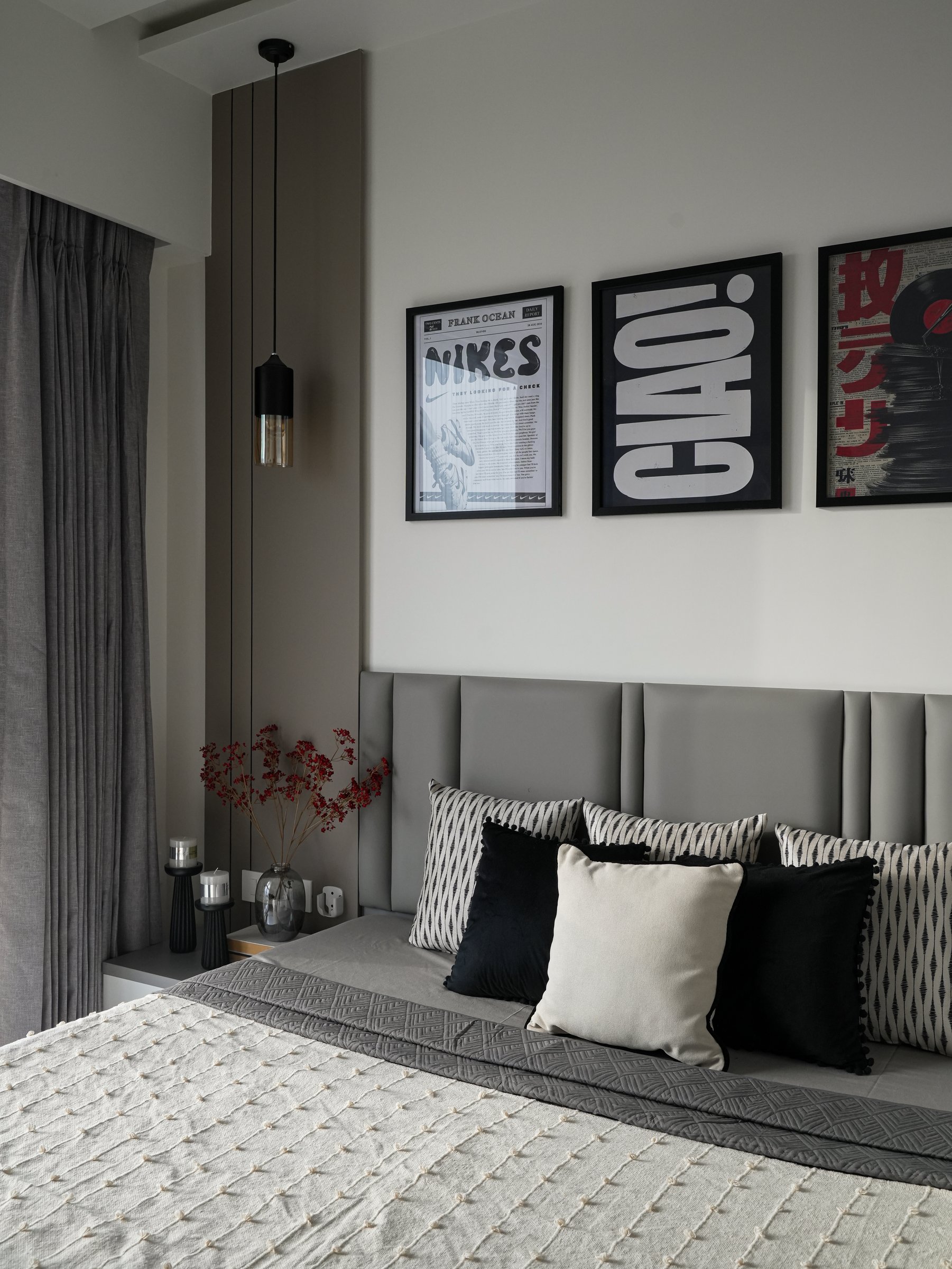 The second bedroom shifts register, pairing a channel-tufted grey headboard with a trio of graphic monochrome prints